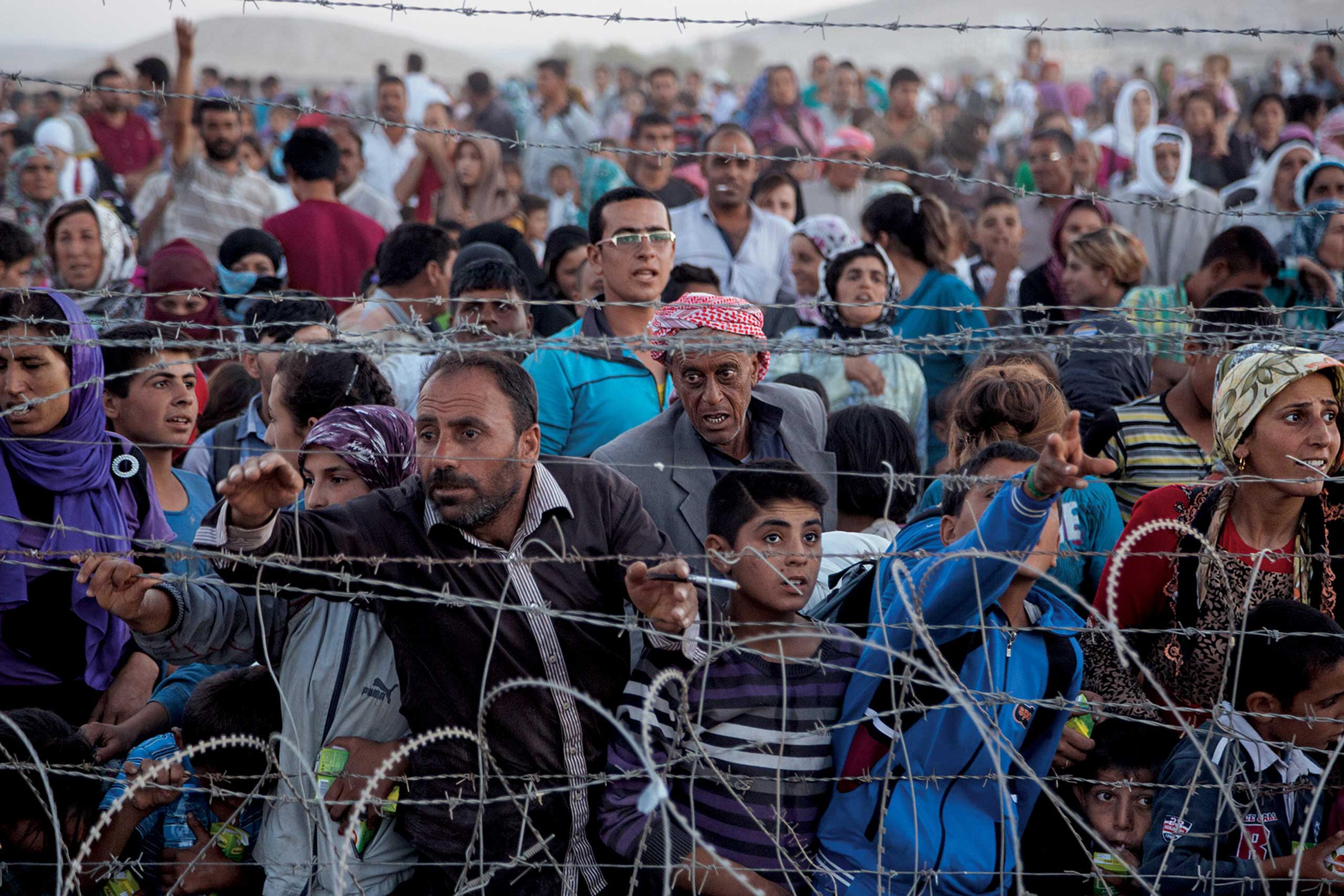 From the March issue of National Geographic magazine: Fleeing Terror, Finding RefugeWith their homes in Ayn al Arab, Syria, under attack, ethnic Kurds push toward a barbed wire fence at the Turkish border.