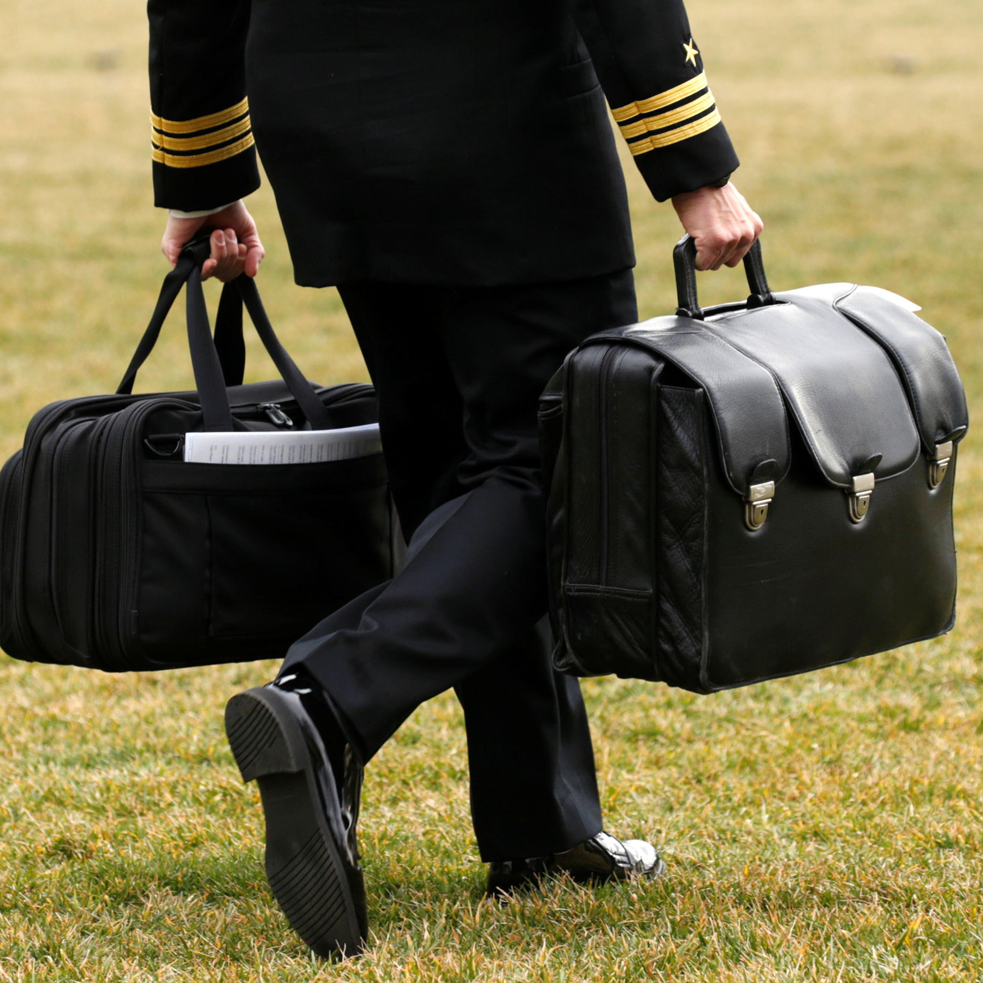 A military aide carries the "football" as Trump departs the White House in Washington