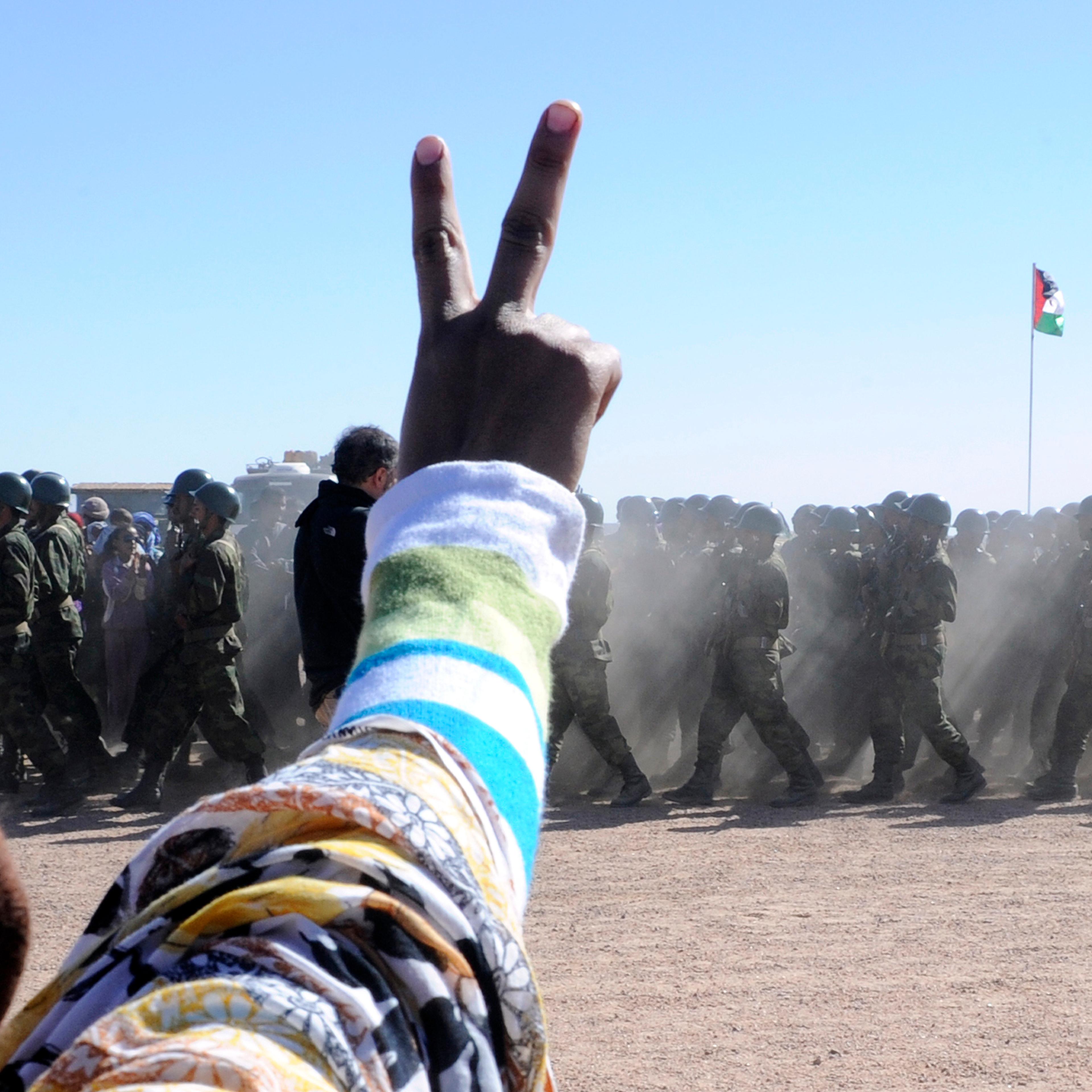 A man flashes a v-sign as soldiers from