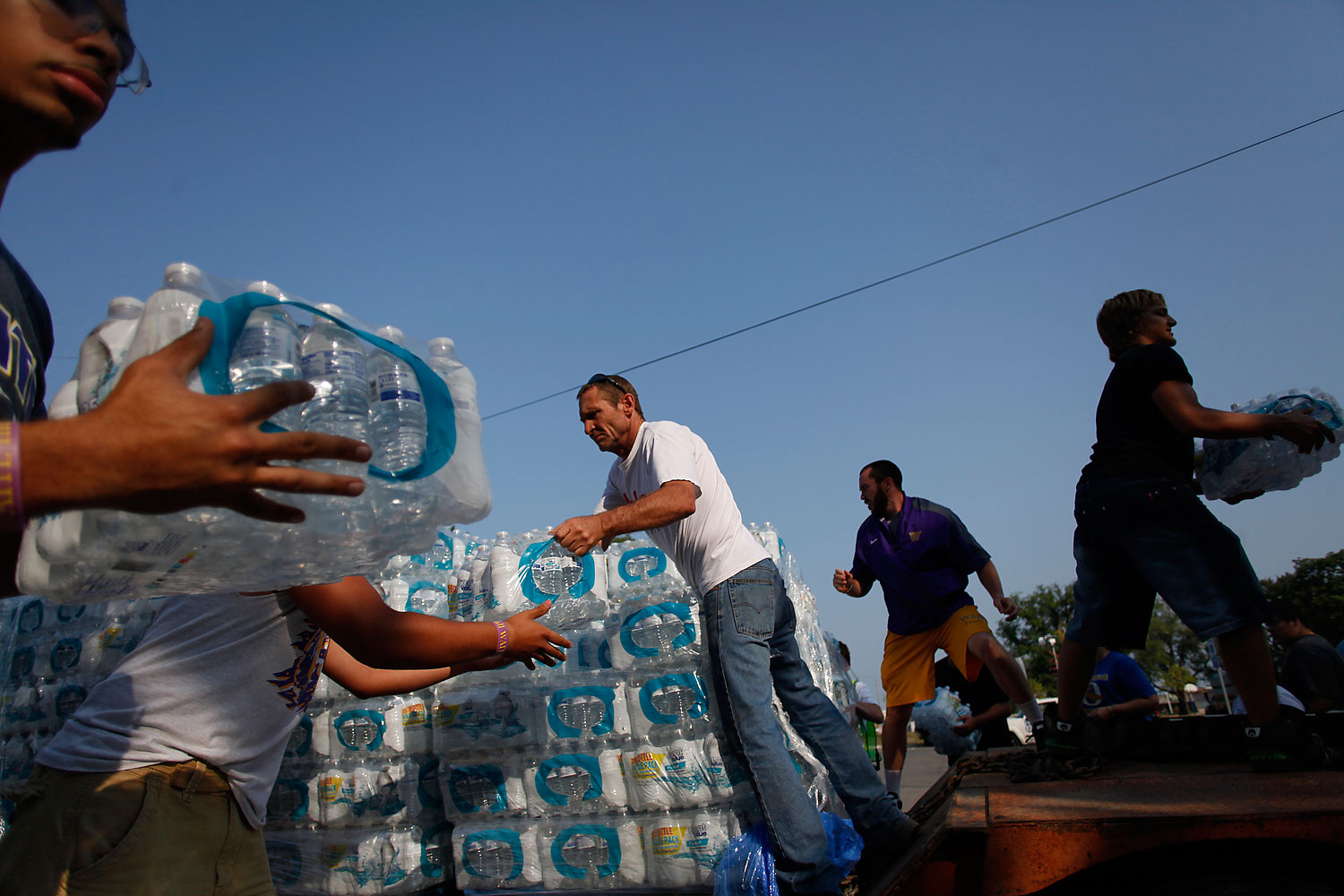 Volunteers unload drinking water from a truck outside Waite High School in Toledo,