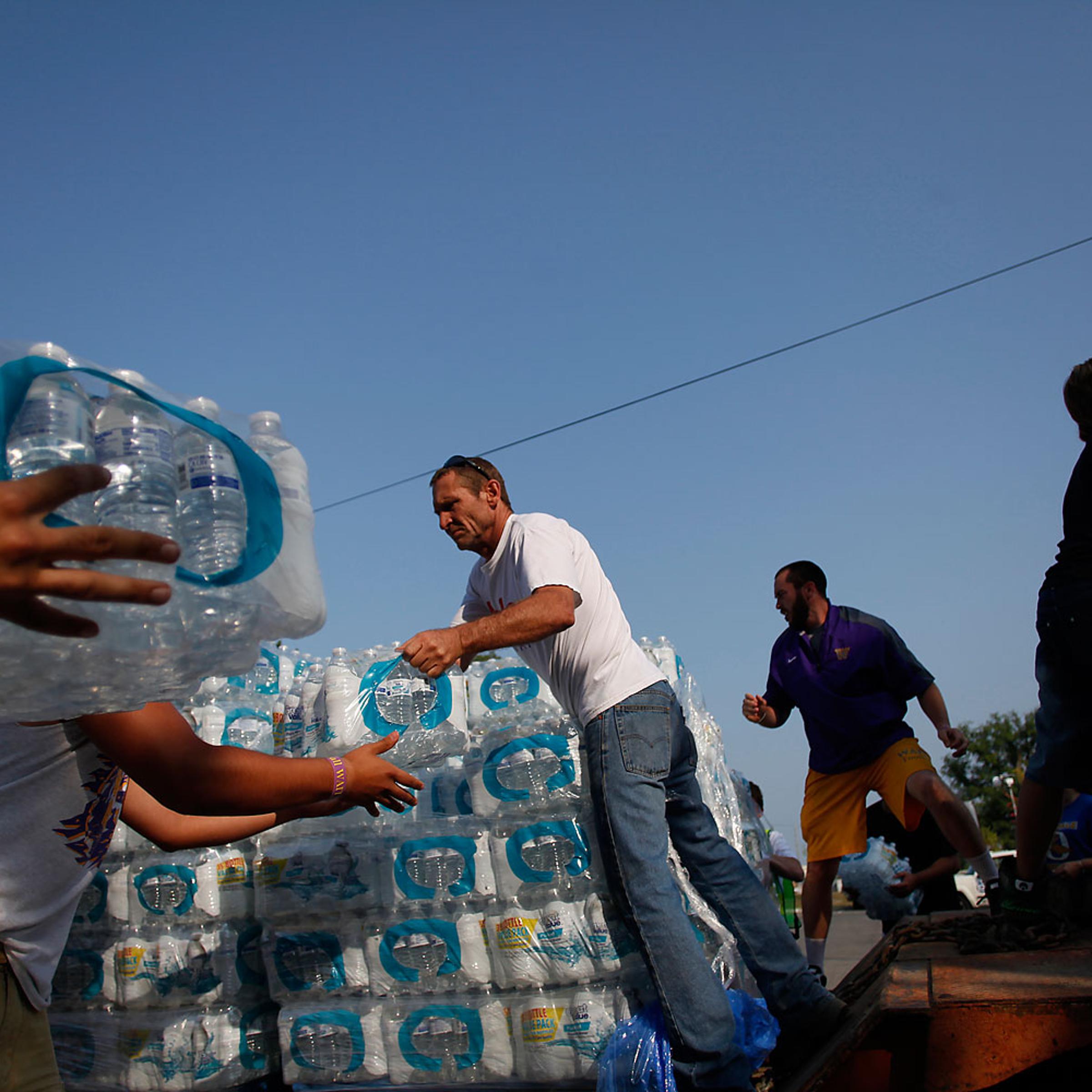 Volunteers unload drinking water from a truck outside Waite High School in Toledo,