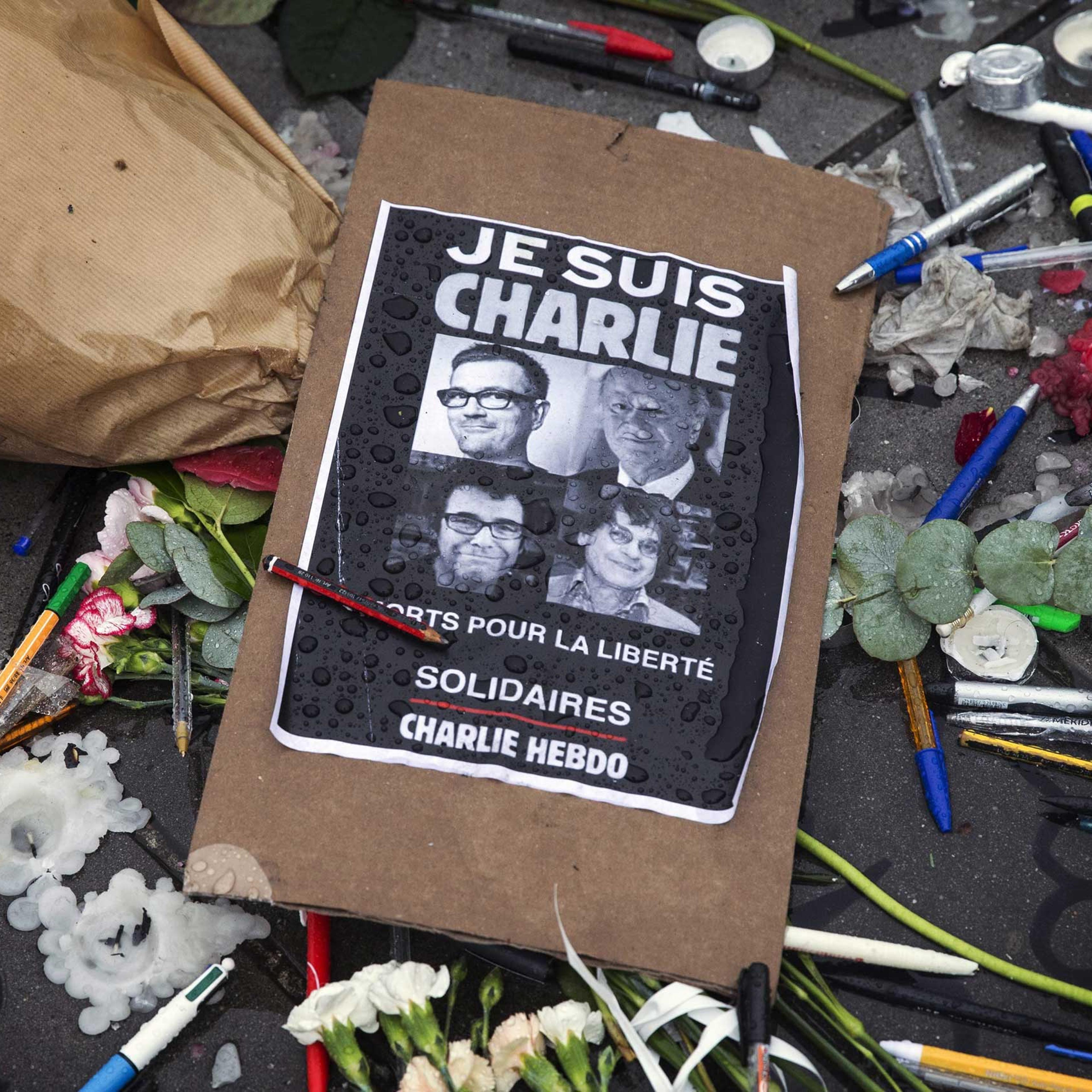 A poster reads 'Je suis Charlie' (I am Charlie) amid symbolic pens and pencils on Place de la Republique as people gather for a minute of silence commemorating those killed in a shooting at French satirical magazine 'Charlie Hebdo', in Paris, Jan. 8, 201