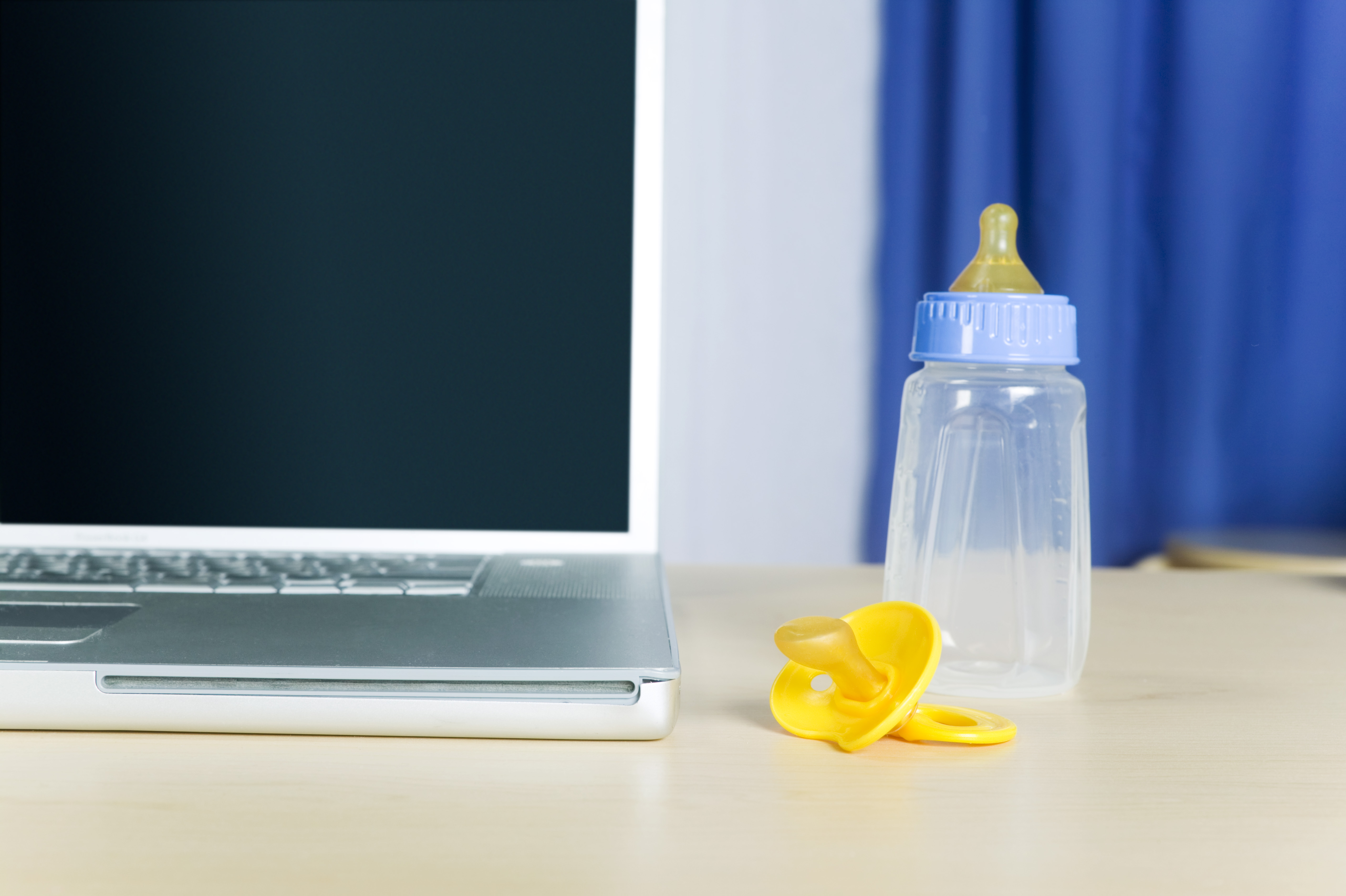 Computer by baby bottle and pacifier