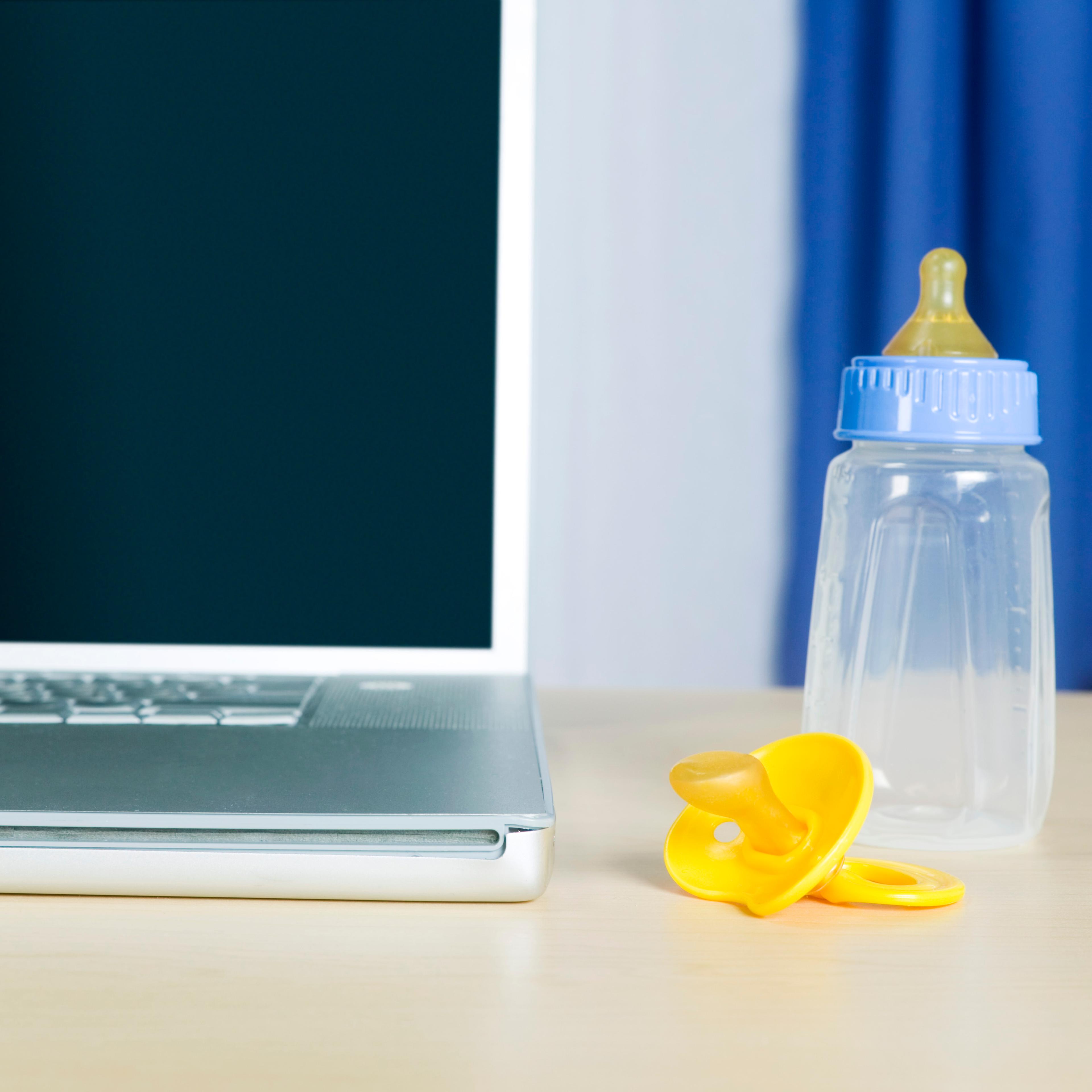 Computer by baby bottle and pacifier