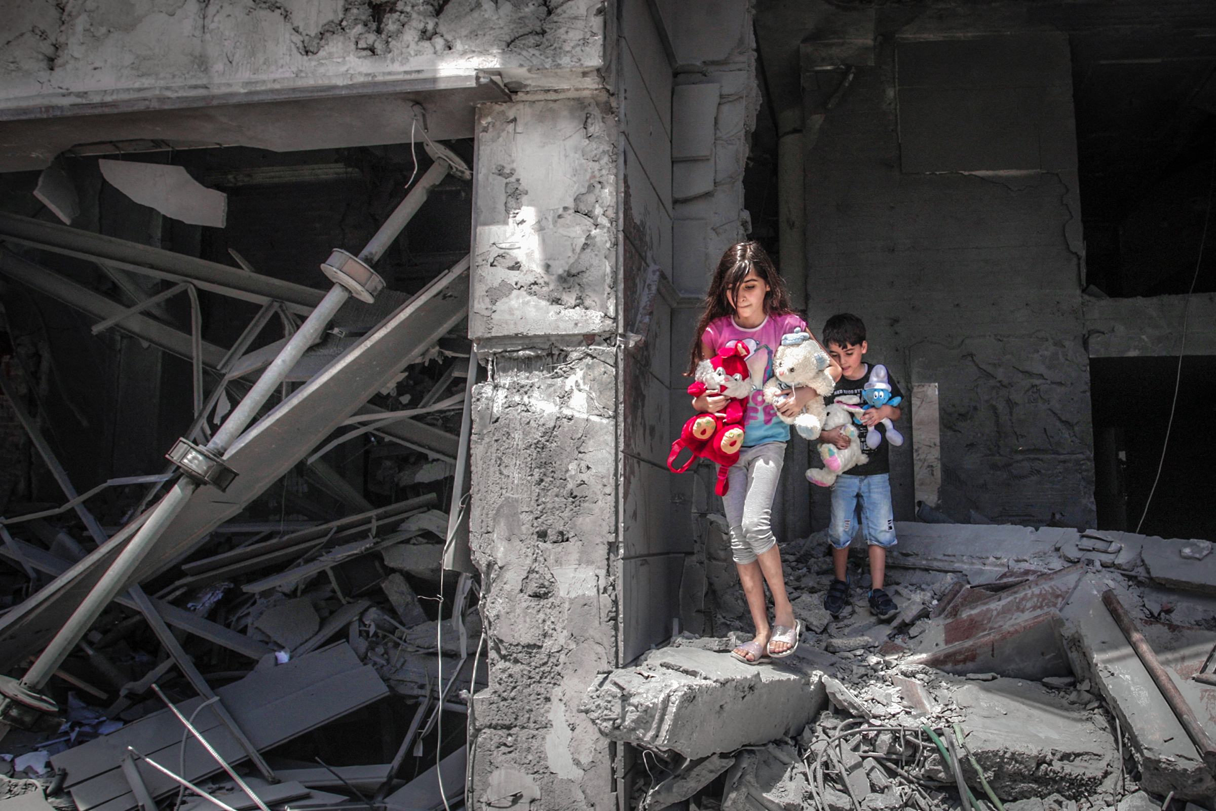 Palestinian children salvage toys from their home at the Al-Jawhara Tower, which was heavily damaged by Israeli bombardment, in Gaza City on May 17, 2021.