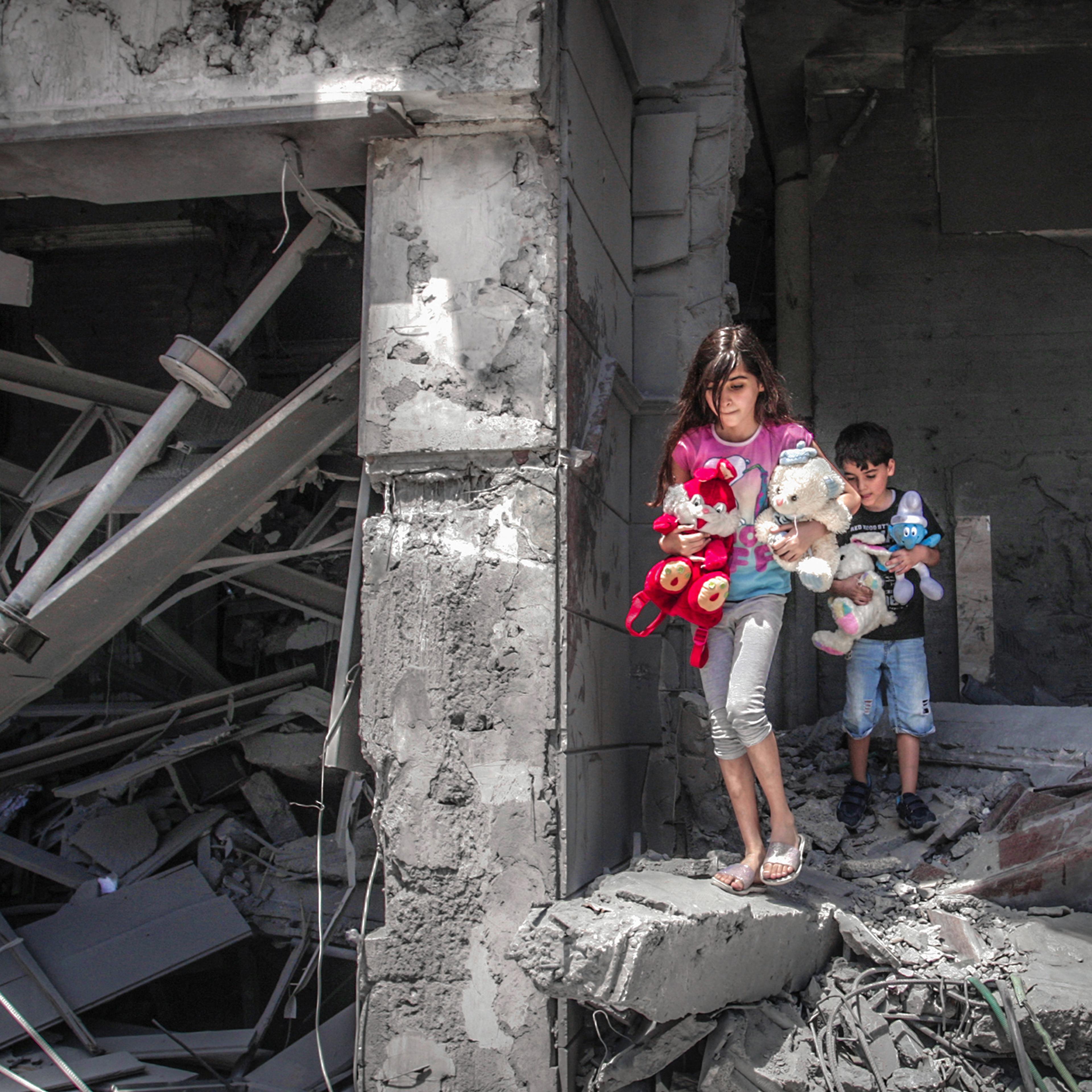 Palestinian children salvage toys from their home at the Al-Jawhara Tower, which was heavily damaged by Israeli bombardment, in Gaza City on May 17, 2021.