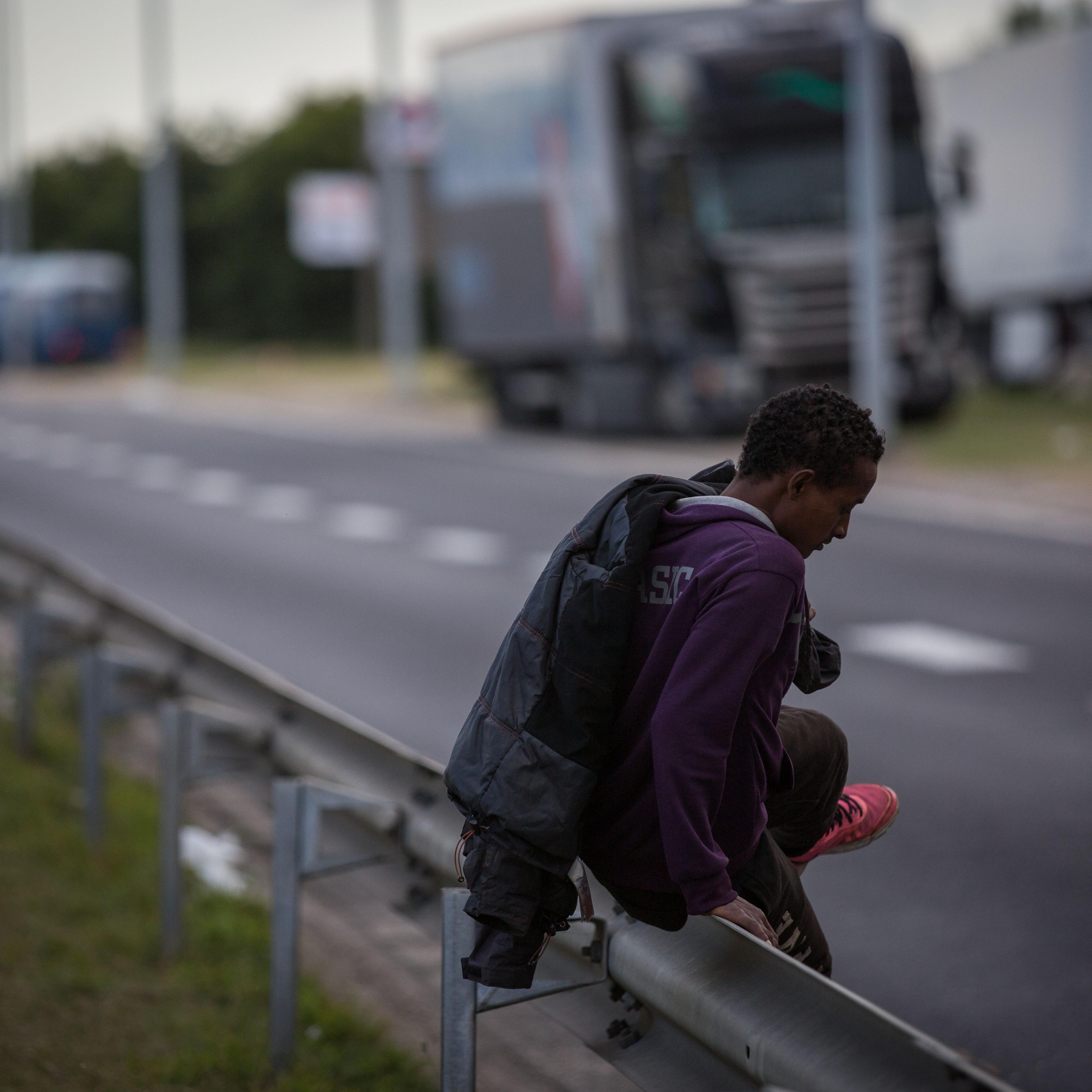 A man climbs a barrier on the side of a road leading to the Eurotunnel terminal in Coquelles on July 30, 2015 in Calais, France.