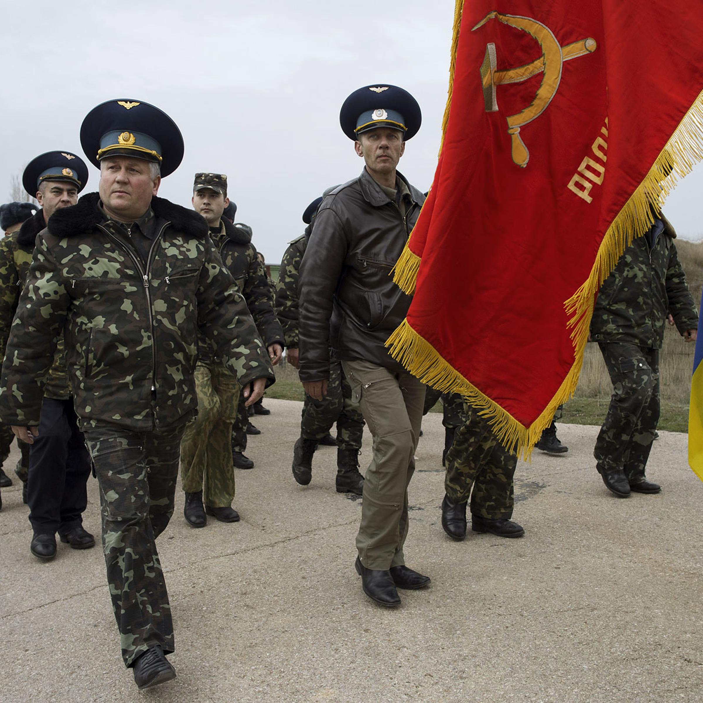 Unarmed Ukrainian soldiers, carrying a Soviet air-regiment banner, approach Russian positions on the perimeter of the contested Belbek air-force base in Crimea, Ukraine, on March 4, 2014.