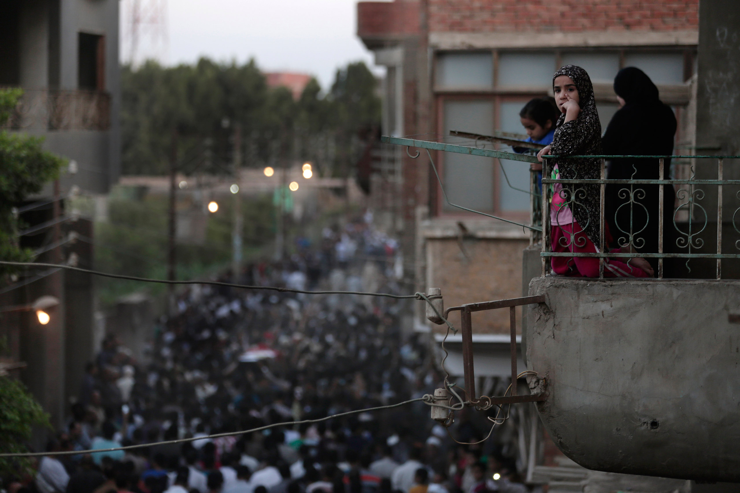 Egyptians mourn as they watch from their balcony during the funeral procession of 1st Lt. Mohammed Adel Abdel Azeem, killed in Wednesday's attack by Islamic militants in the Sinai, at his home village Tant Al Jazeera in Qalubiyah, north of Cairo, Egypt, 