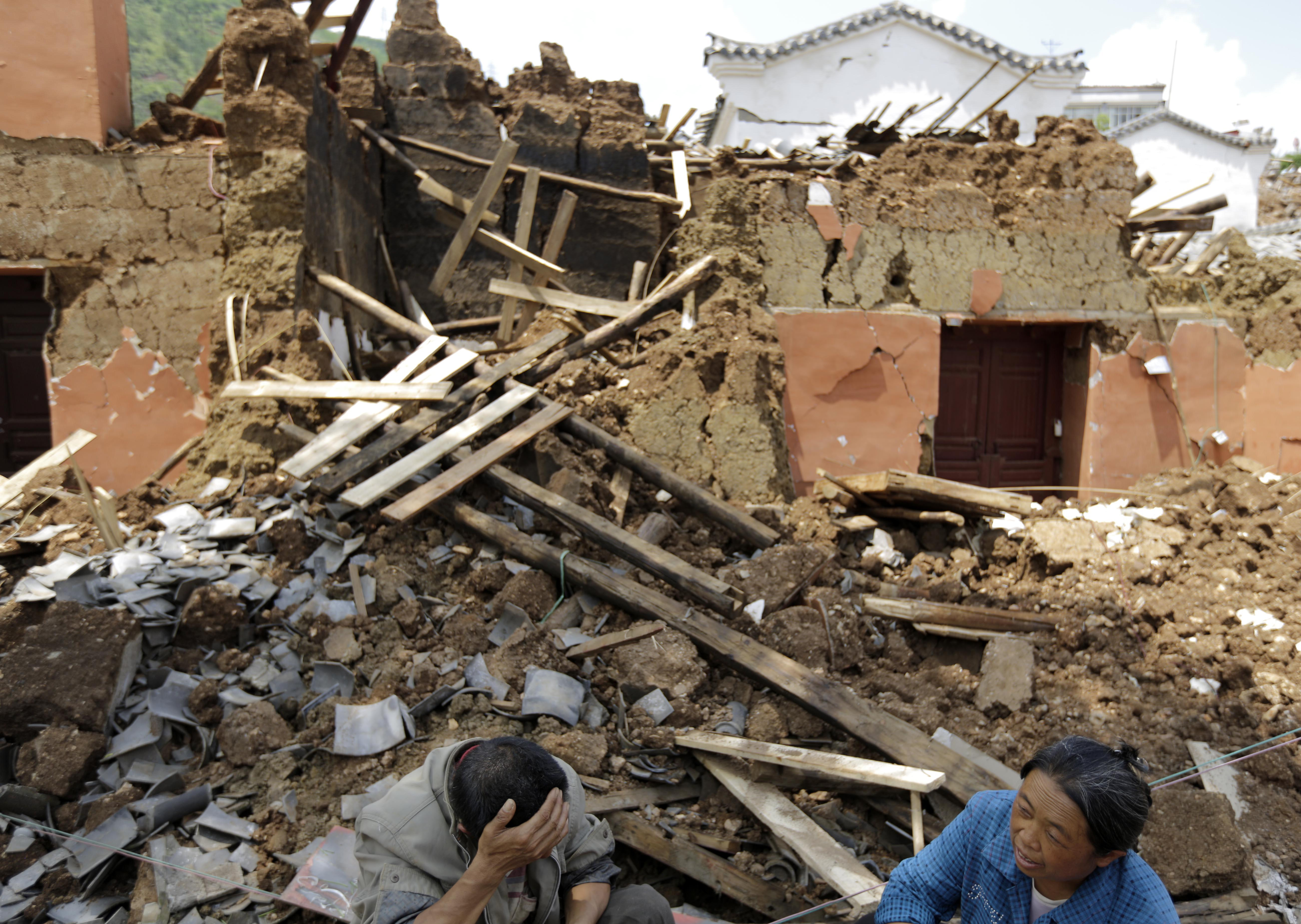 Villagers sit in front of their destroyed house following a massive earthquake in the town of Longtoushan in Ludian County in southwest China's Yunnan Province on Aug. 5, 2014.
