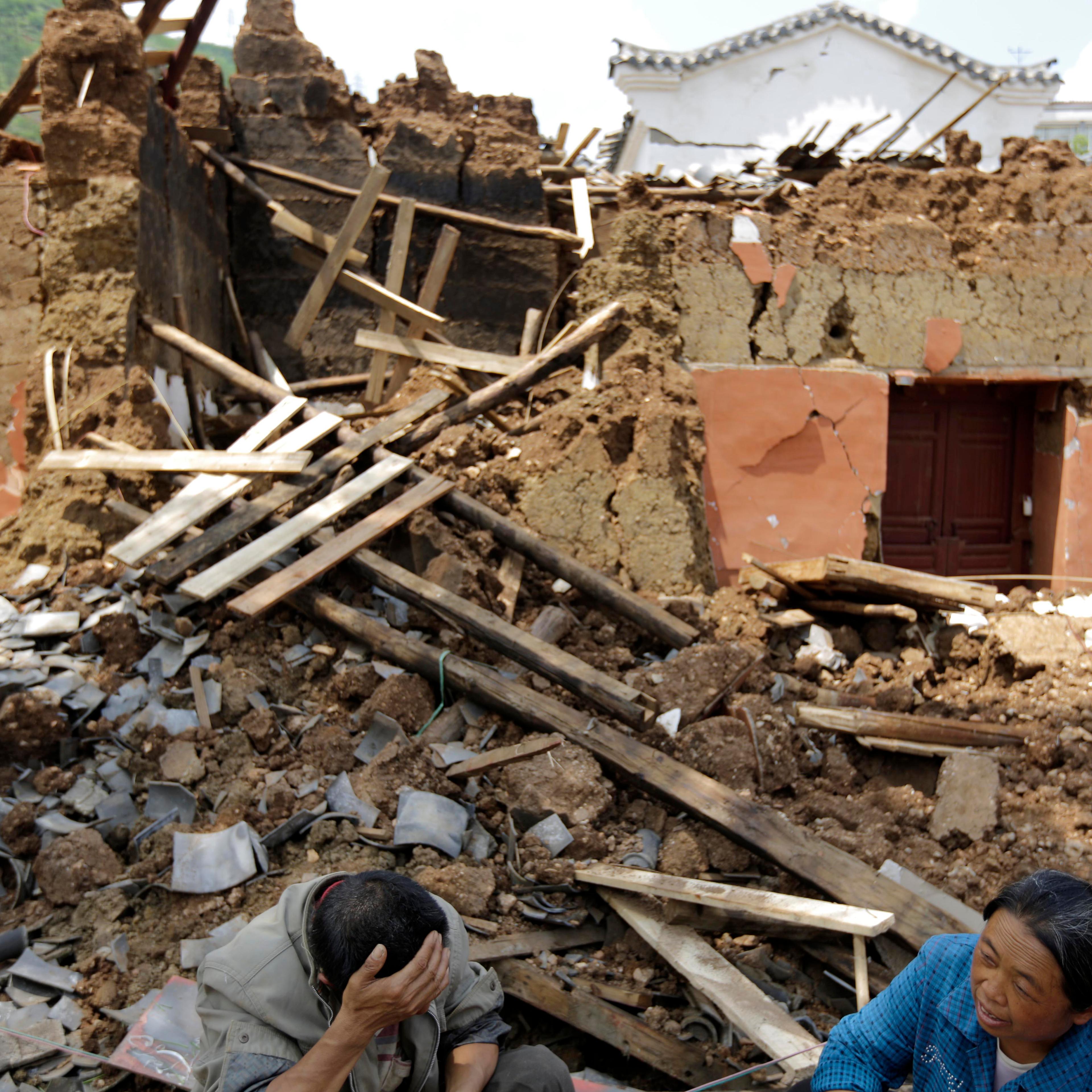 Villagers sit in front of their destroyed house following a massive earthquake in the town of Longtoushan in Ludian County in southwest China's Yunnan Province on Aug. 5, 2014.
