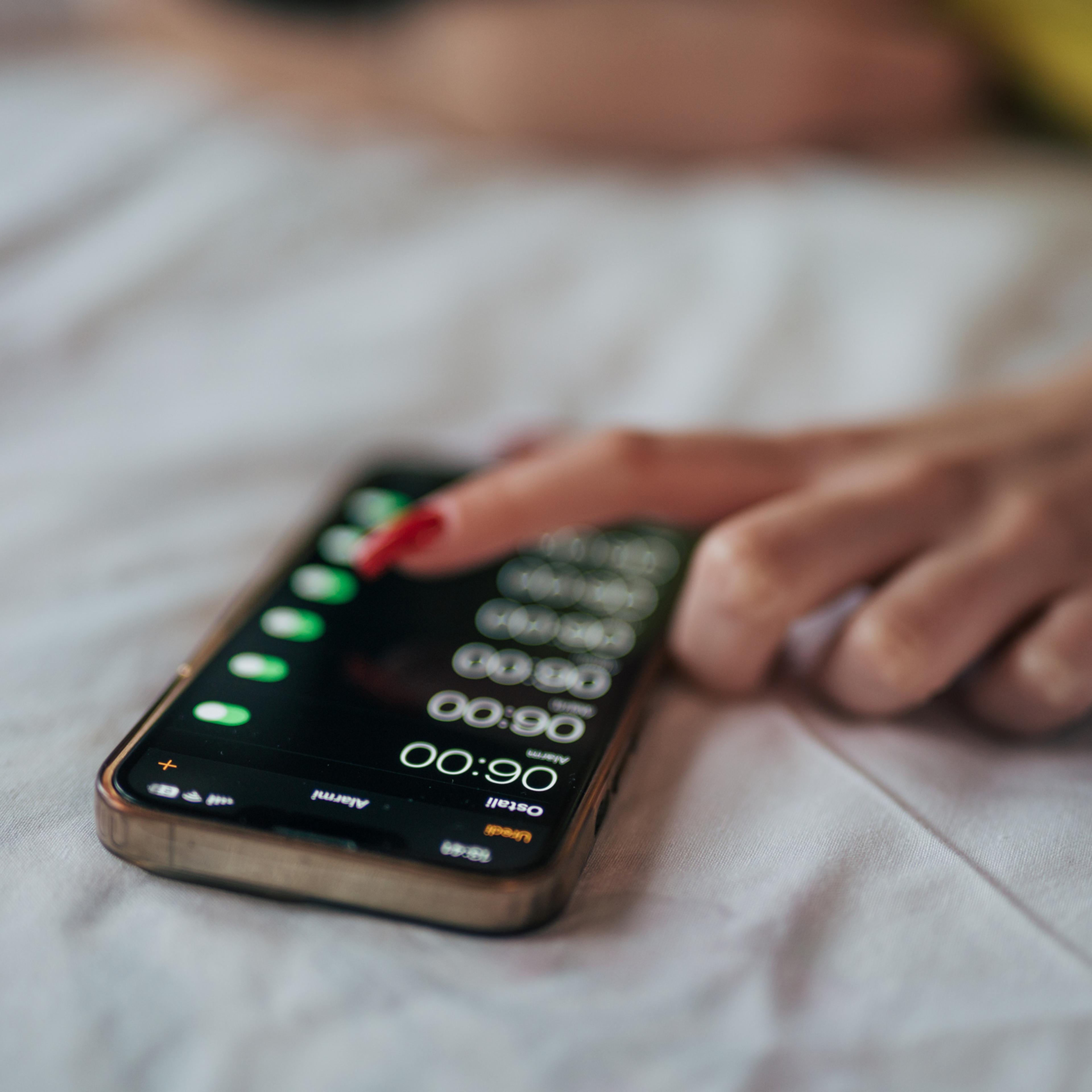 A young woman snooze an alarm on her phone in the morning