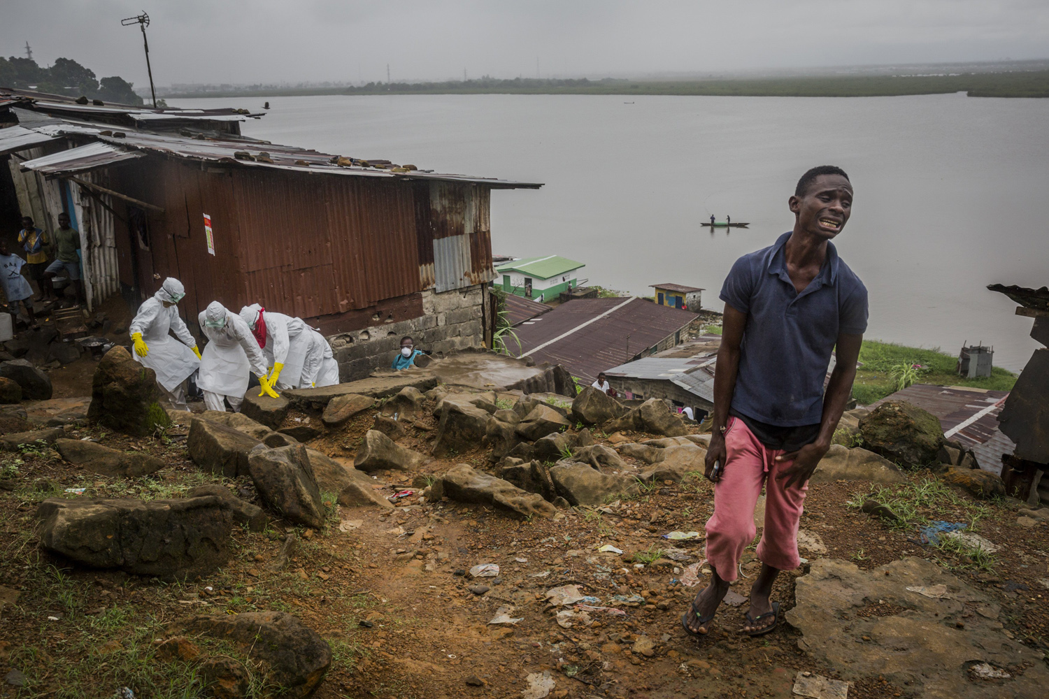 Eric Gweah, 25, grieves as he watches members of a Red Cross burial team carry the body his father, Ofori Gweah, 62, a suspected Ebola victim, in a riverside area called Rock Spring Valley in central Monrovia, Liberia, Sept. 18, 2014.