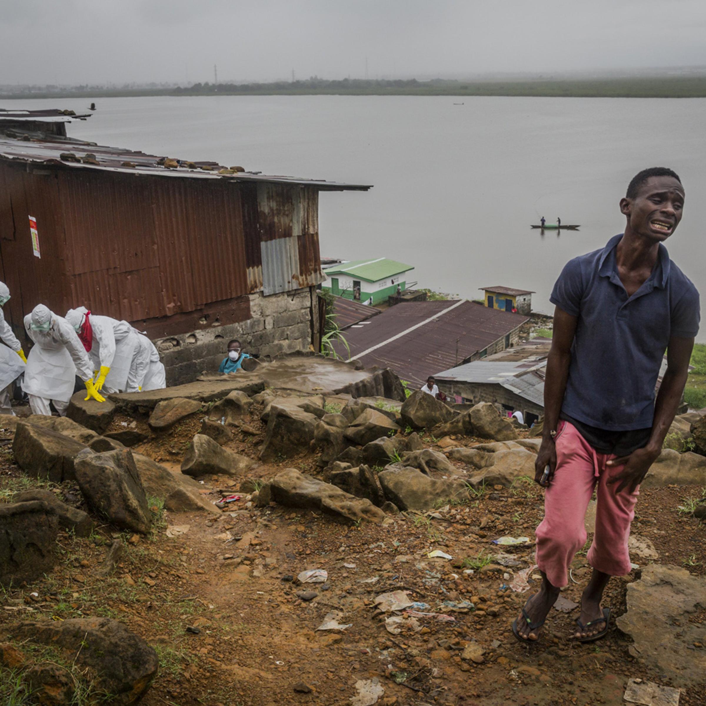 Eric Gweah, 25, grieves as he watches members of a Red Cross burial team carry the body his father, Ofori Gweah, 62, a suspected Ebola victim, in a riverside area called Rock Spring Valley in central Monrovia, Liberia, Sept. 18, 2014.