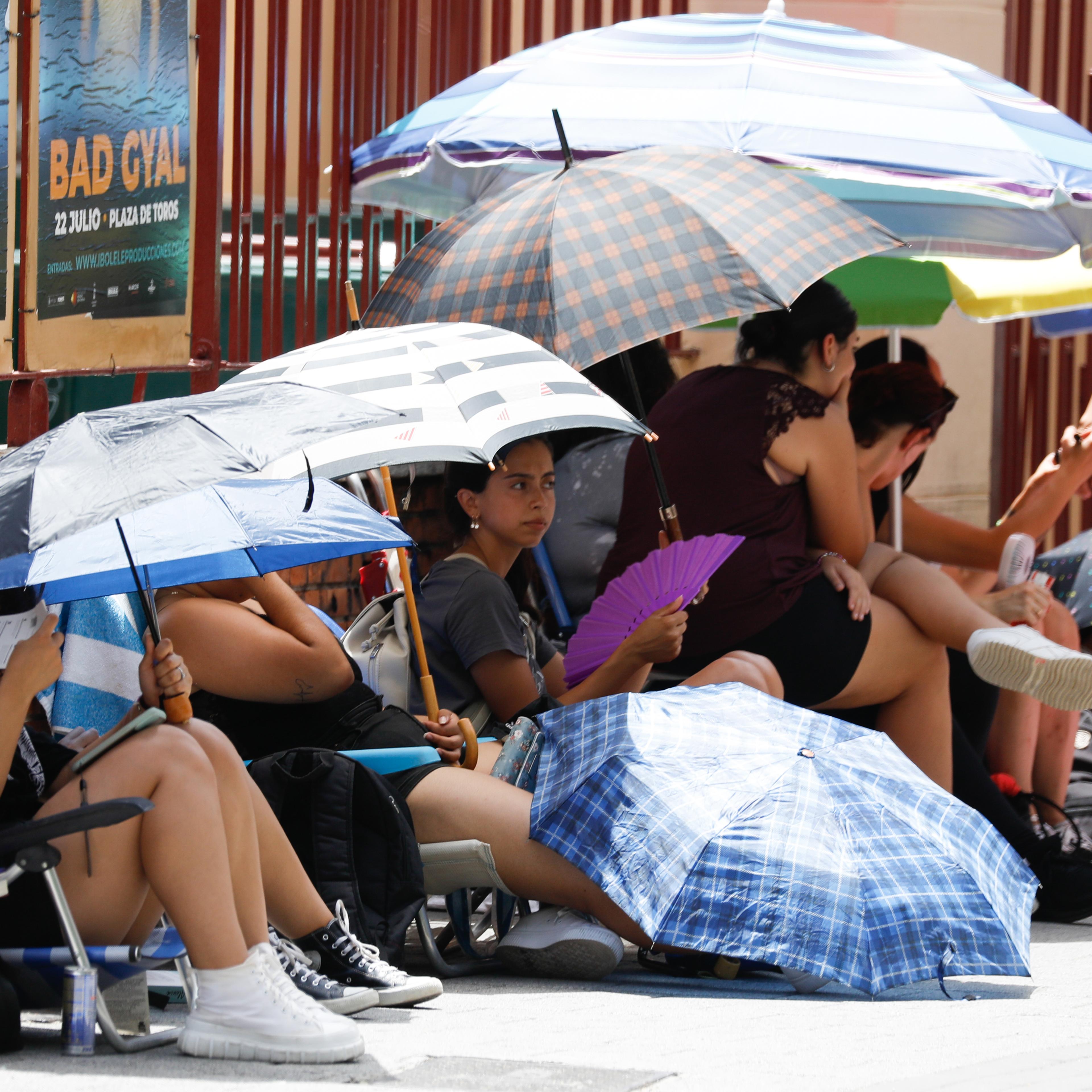 People take shelter from the heat under umbrellas, in Murcia, Spain.