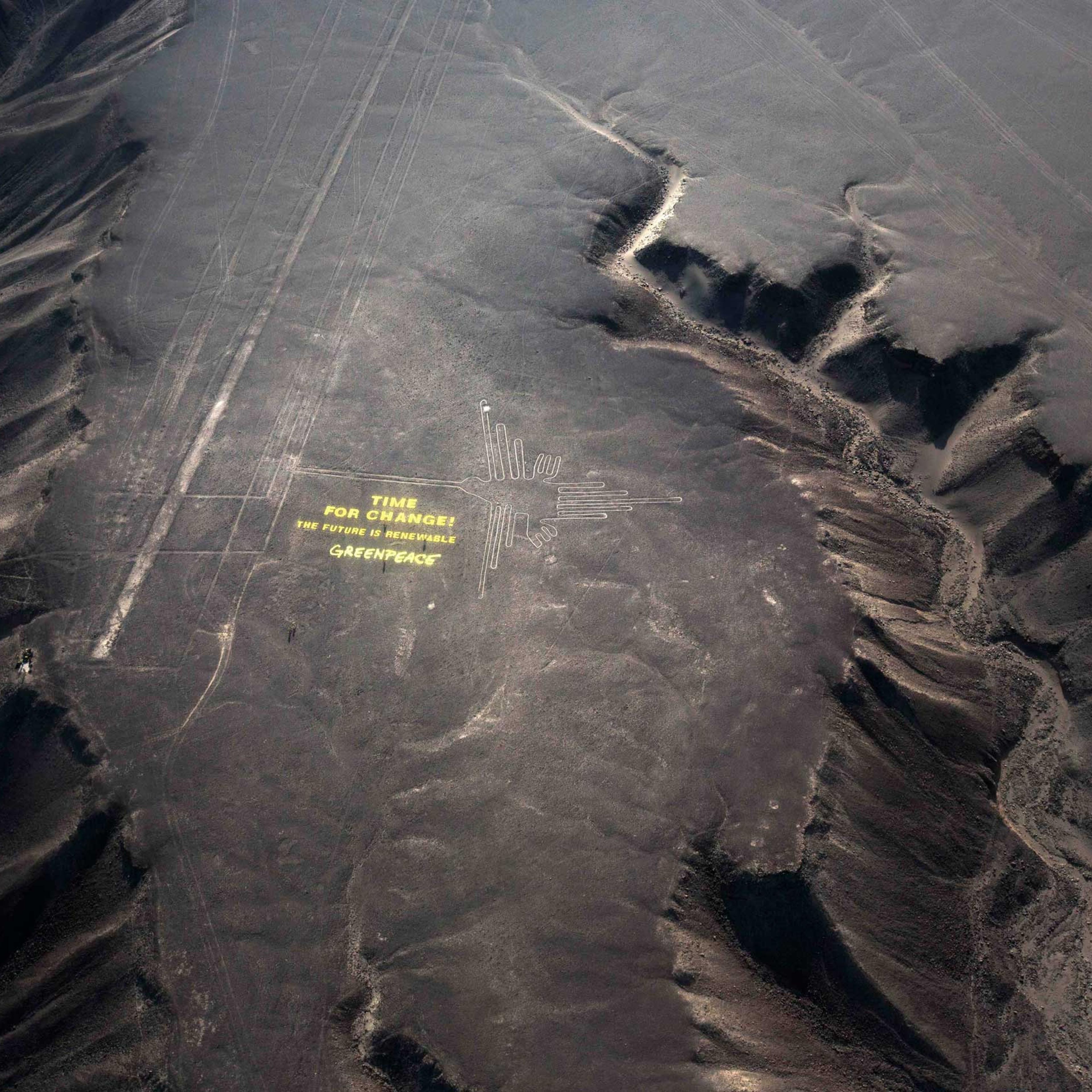 Greenpeace activists stand next to massive letters delivering the message "Time for Change: The Future is Renewable," next to the hummingbird geoglyph in Nazca in Peru,, Dec. 8, 2014.