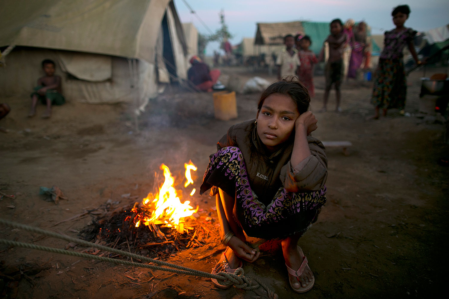 A Rohingya woman sits by a fire at a crowded internally displaced persons (IDP) camp Nov. 23, 2012 on the outskirts of Sittwe, Burma
