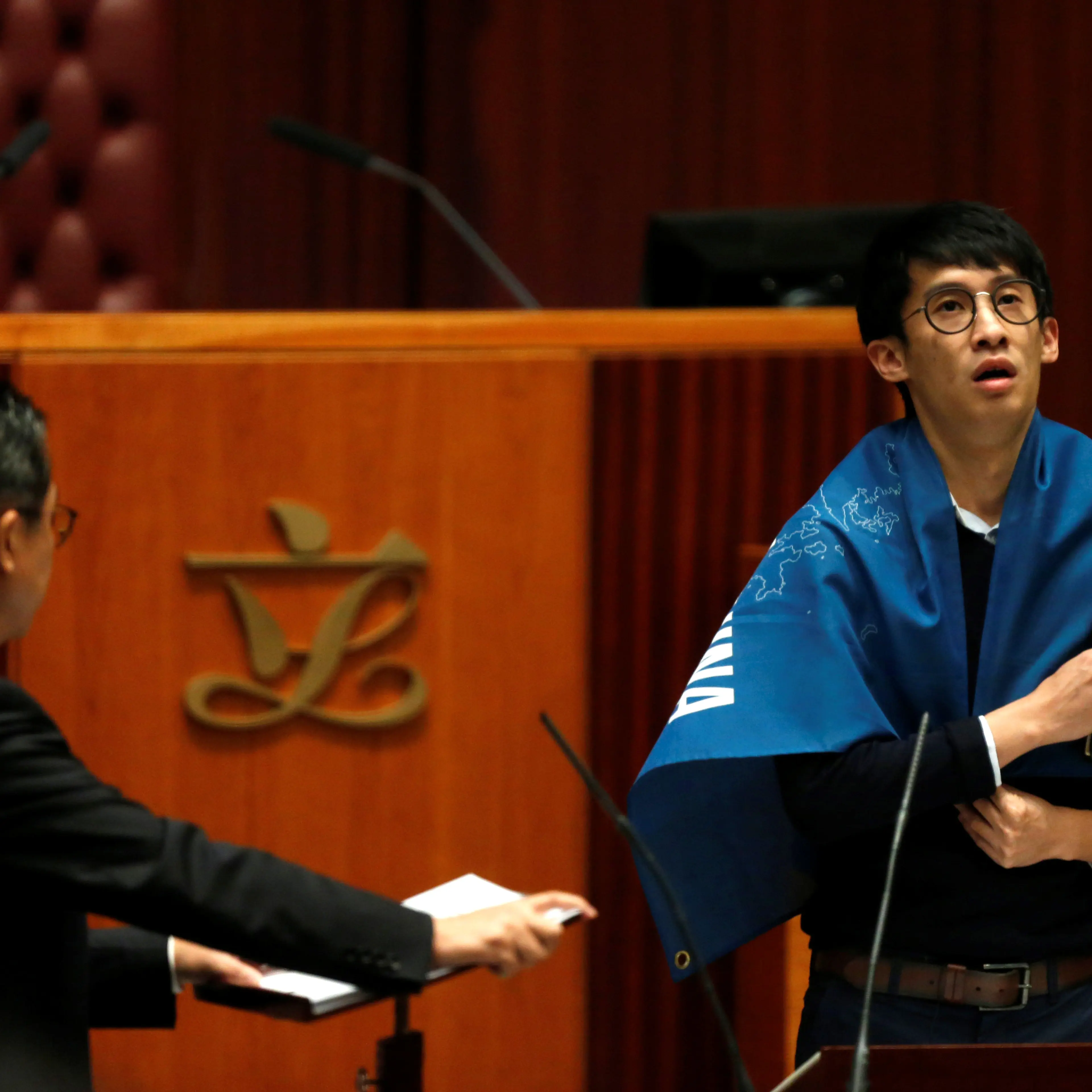 Newly elected lawmaker Baggio Leung wears a banner while taking oath at the Legislative Council in Hong Kong