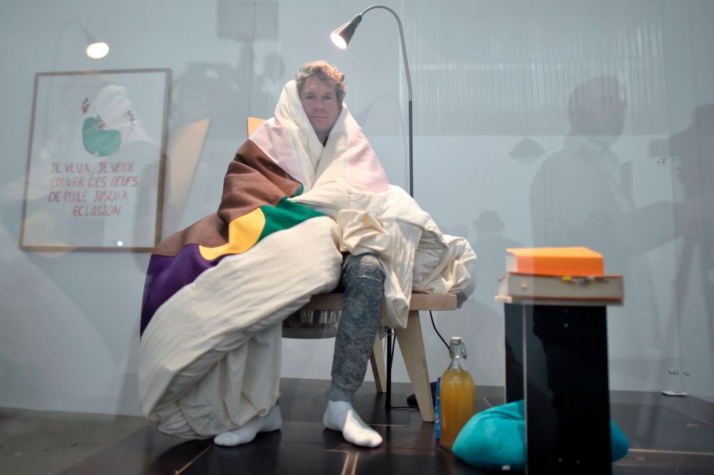 French artist Abraham Poincheval sits on real chicken eggs until they hatch during a performance at the Palais de Tokyo on March 29, 2017 in Paris.