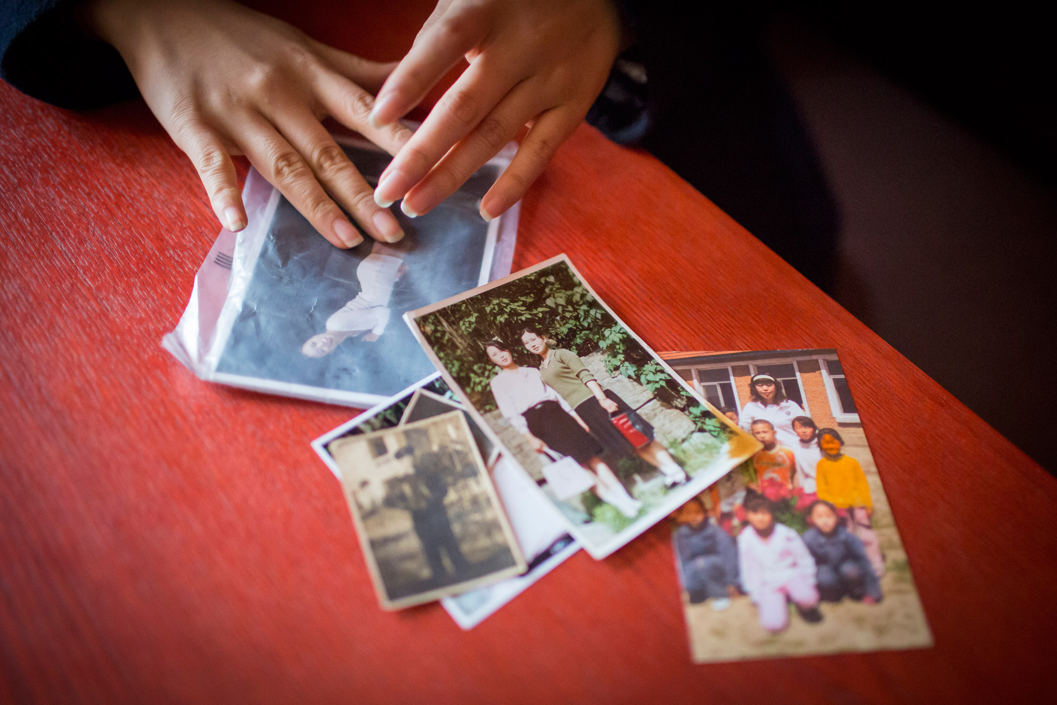 Kyong-ok shows photographs she brought with her on the 10-month journey from North Korea through China, Vietnam and Cambodia on Feb. 1, 2015 in a room cafe in Mia, Seoul, South Korea. They show two of her three sisters, her grandfather in full DPRK milit
