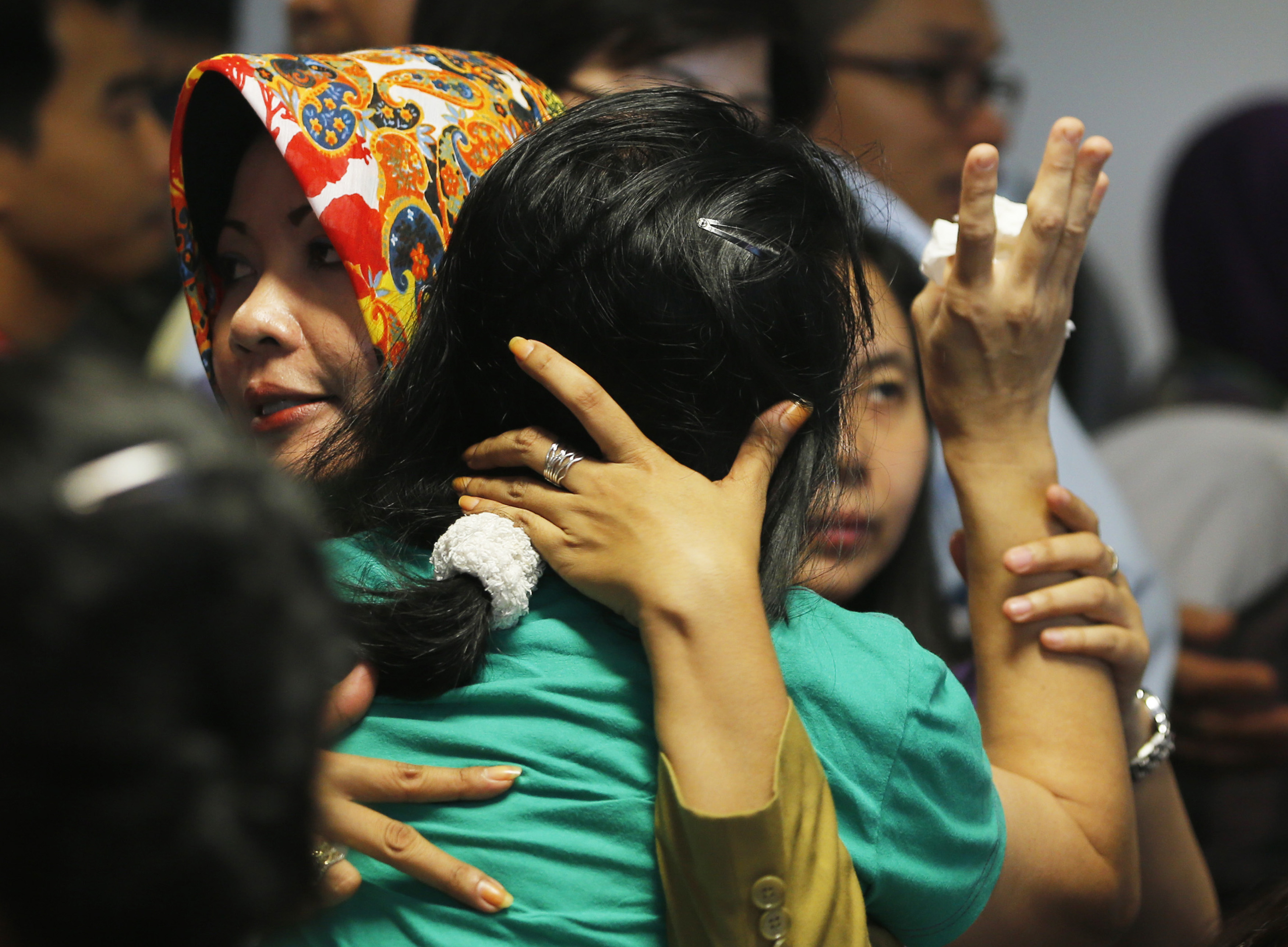 Government official tries to calm a family member of passengers onboard AirAsia flight QZ8501 at a waiting area in Juanda International Airport