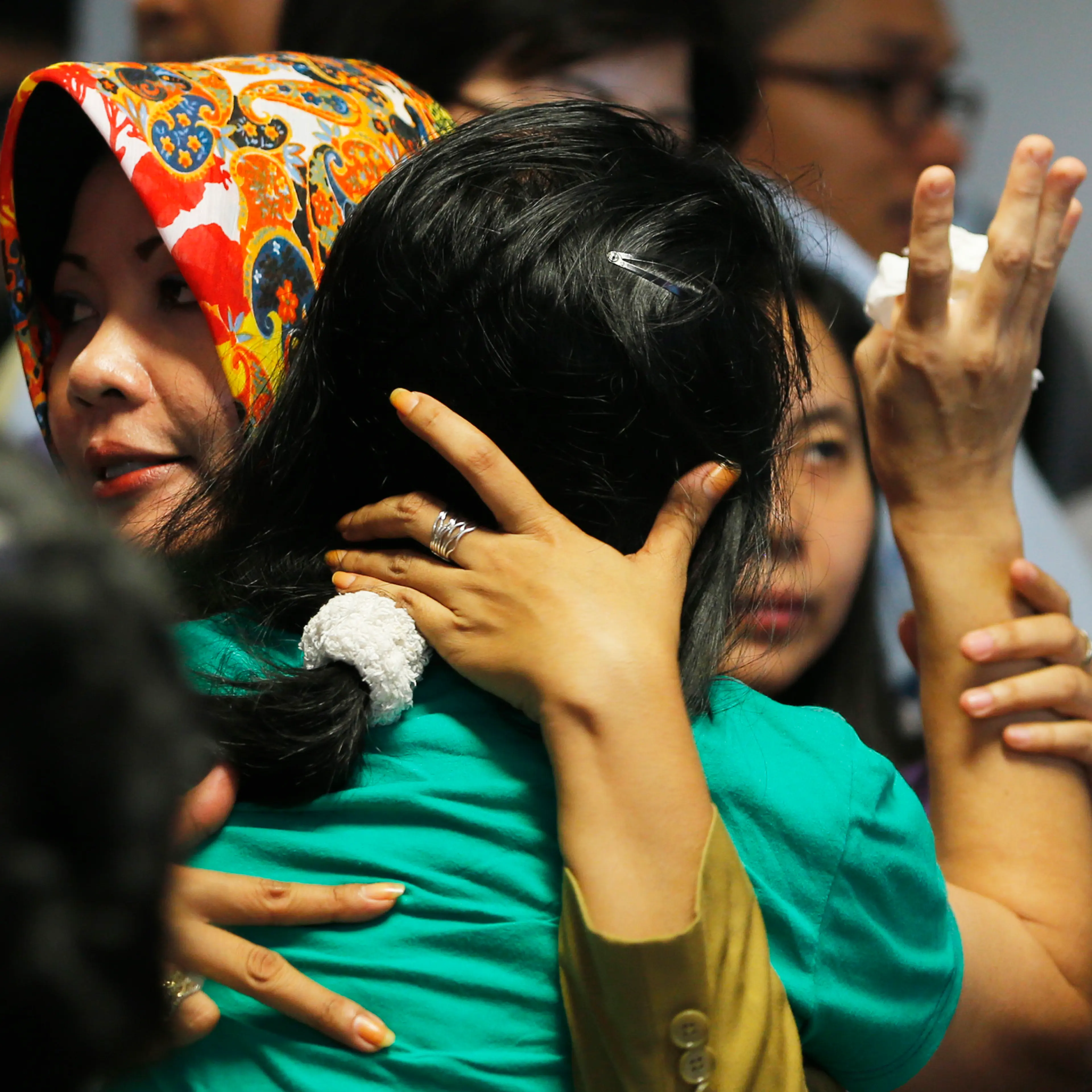 Government official tries to calm a family member of passengers onboard AirAsia flight QZ8501 at a waiting area in Juanda International Airport