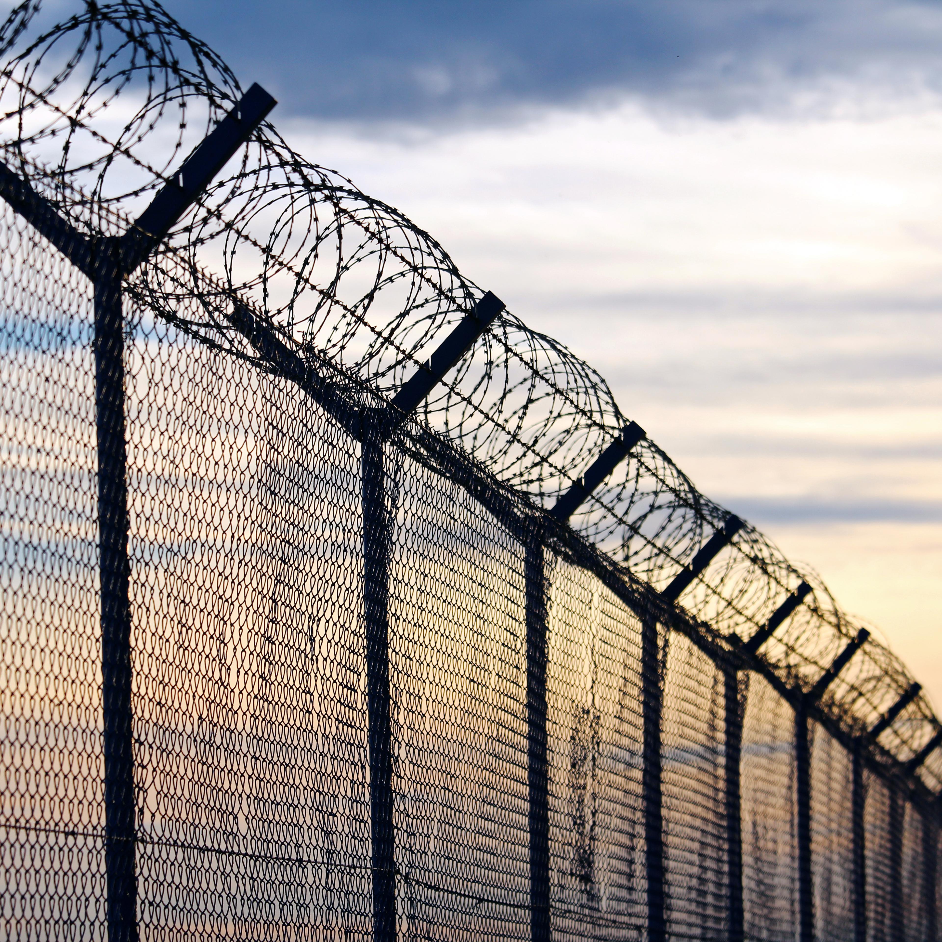 Silhouette of Barbed Wire fence against a Cloudy Sky
