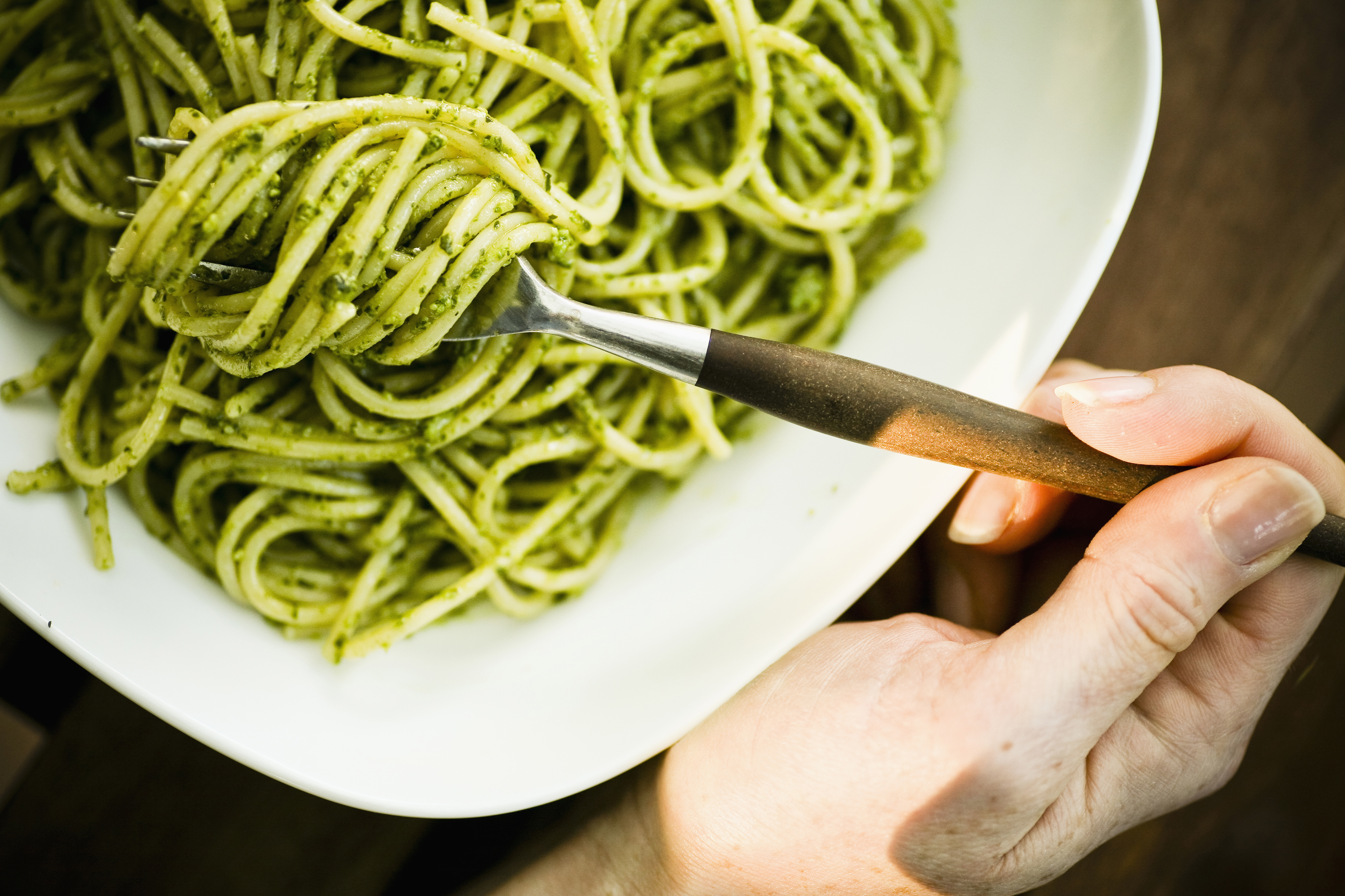 A young woman enjoys a bowl of organic pesto pasta in Seattle WA.