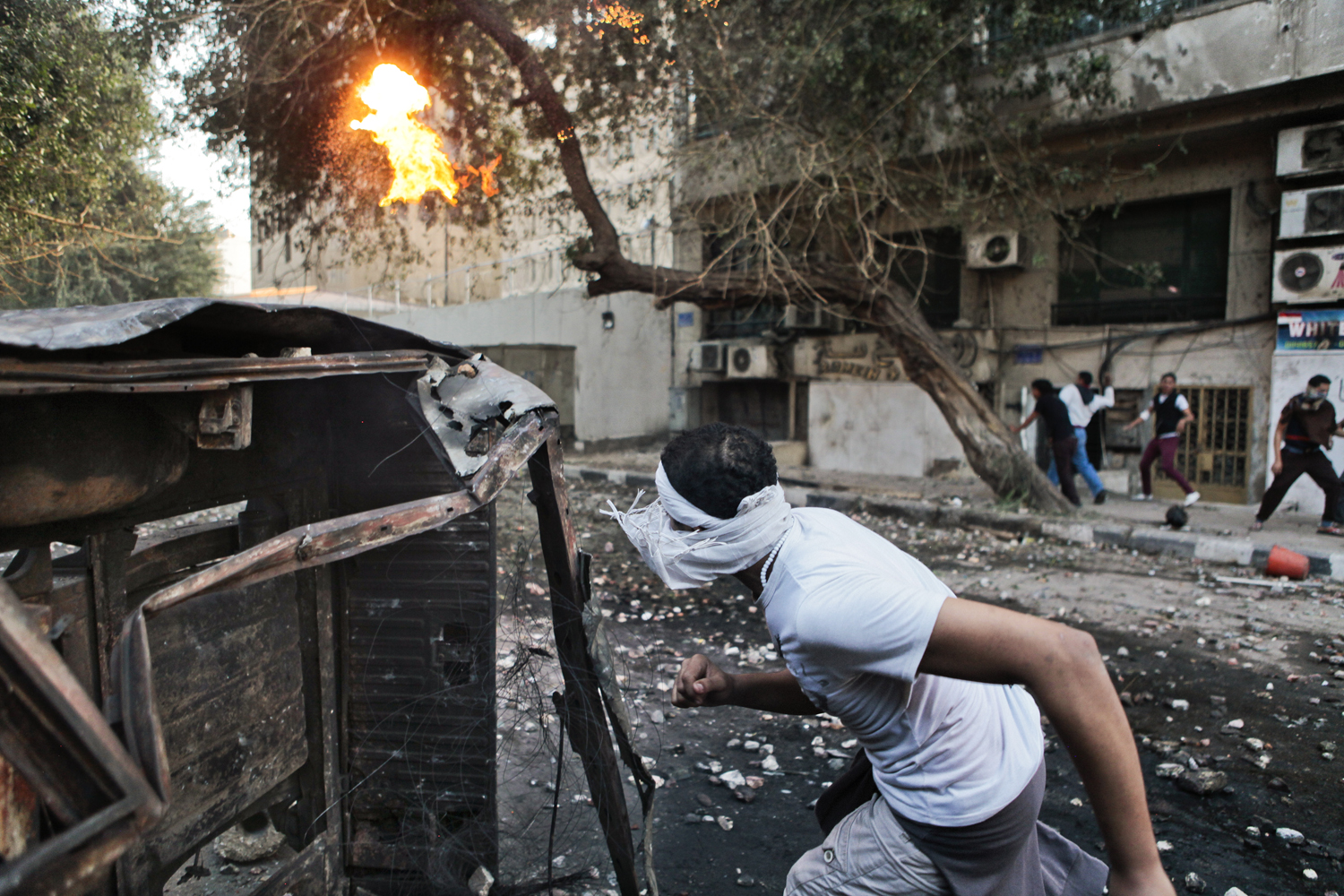Nov. 28, 2012. An Egyptian protester finds cover behind a destroyed vehicle at the scene of clashes with police near Tahrir Square in Cairo. In conjunction with <a href="http://world.time.com/2012/11/28/morsis-moment/">"Morsi's Moment."</a>
