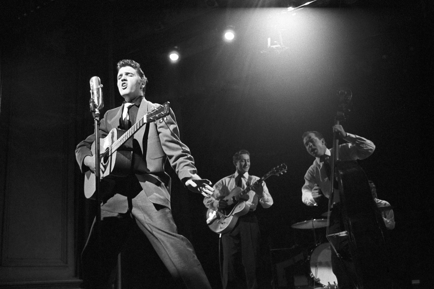 March 17, 1956. Studio 50 in New York. This image became a Swedish postage stamp, representing the 50th anniversary of Rock and Roll. This is the performance on the Dorsey Brothers 'Stage Show.' In the background is Bill Black on bass, Scottie Moore on guitar and, hidden behind the bass, DJ Fontana on drums.
