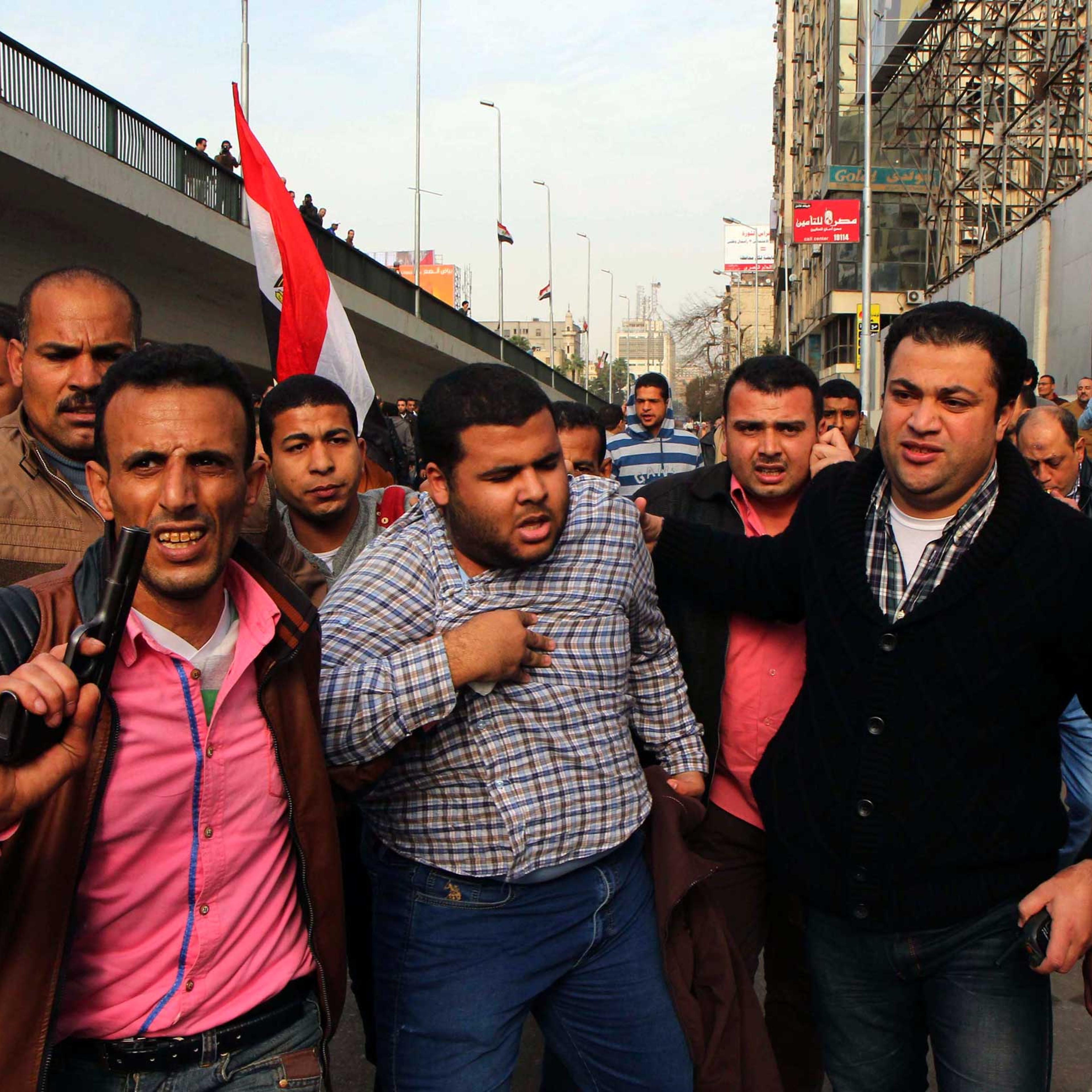 Man holds his chest as he is arrested by plainclothes police in downtown Cairo, Jan. 25, 2015.