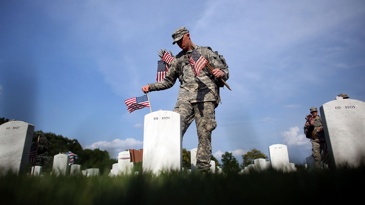 Members of the 3rd U.S. Infantry Regiment place American flags at the graves of U.S. soldiers