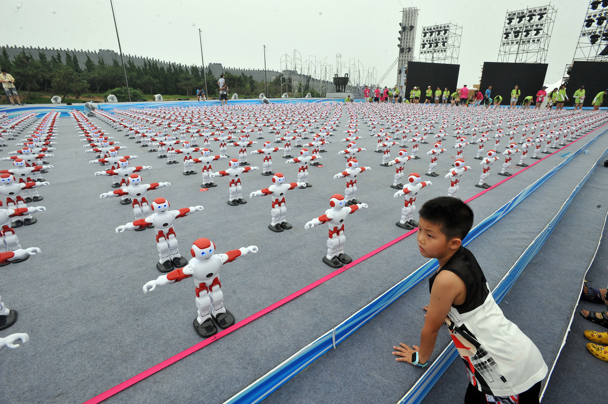 A young boy watches robots dancing during a challenge to set a new Guinness World Record for the most robot dancing simultaneously in Qingdao city, east China's Shandong province, July 30, 2016.