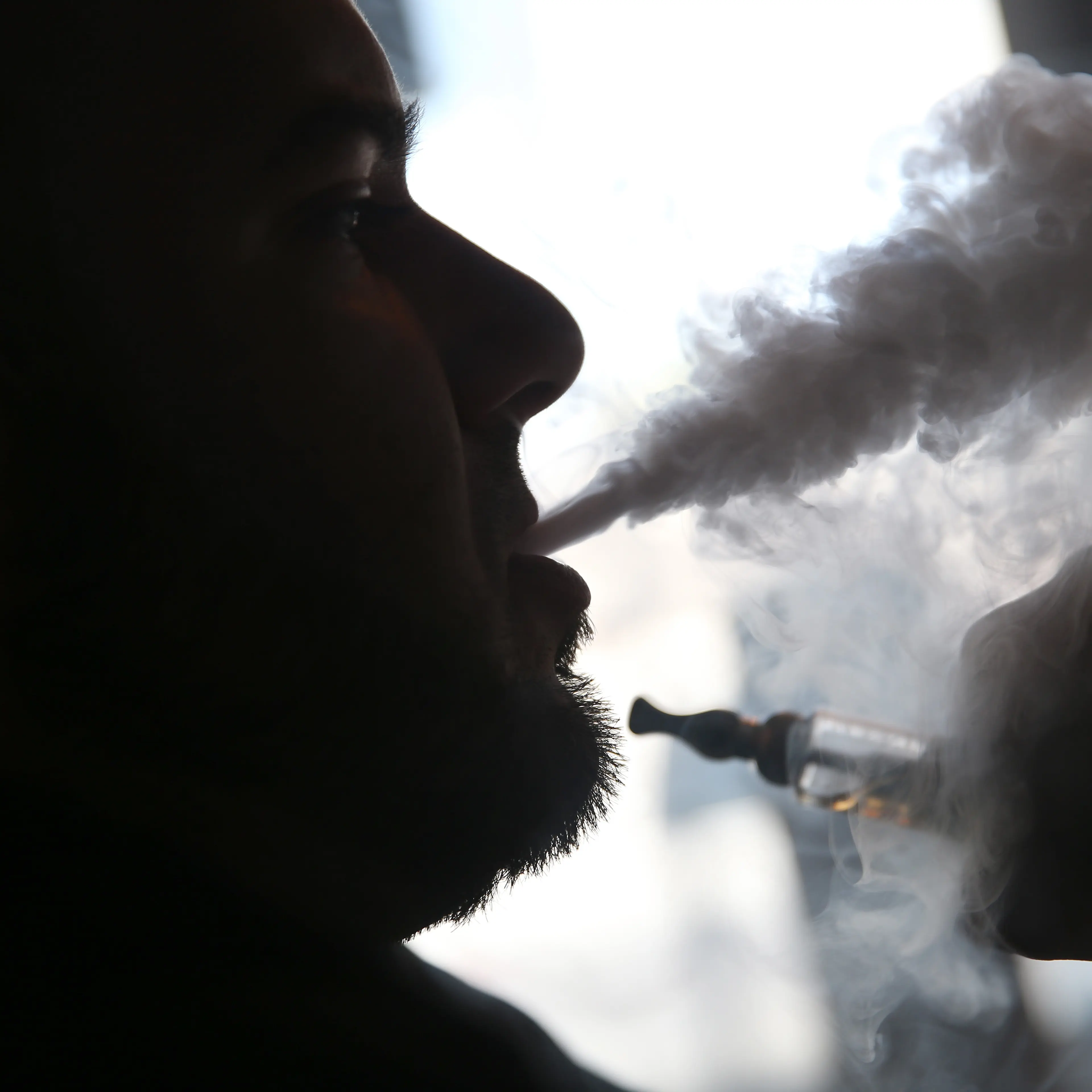 A salesman waits for customers as he enjoys an electronic cigarette at a store in Miami, Florida on April 24, 2014.