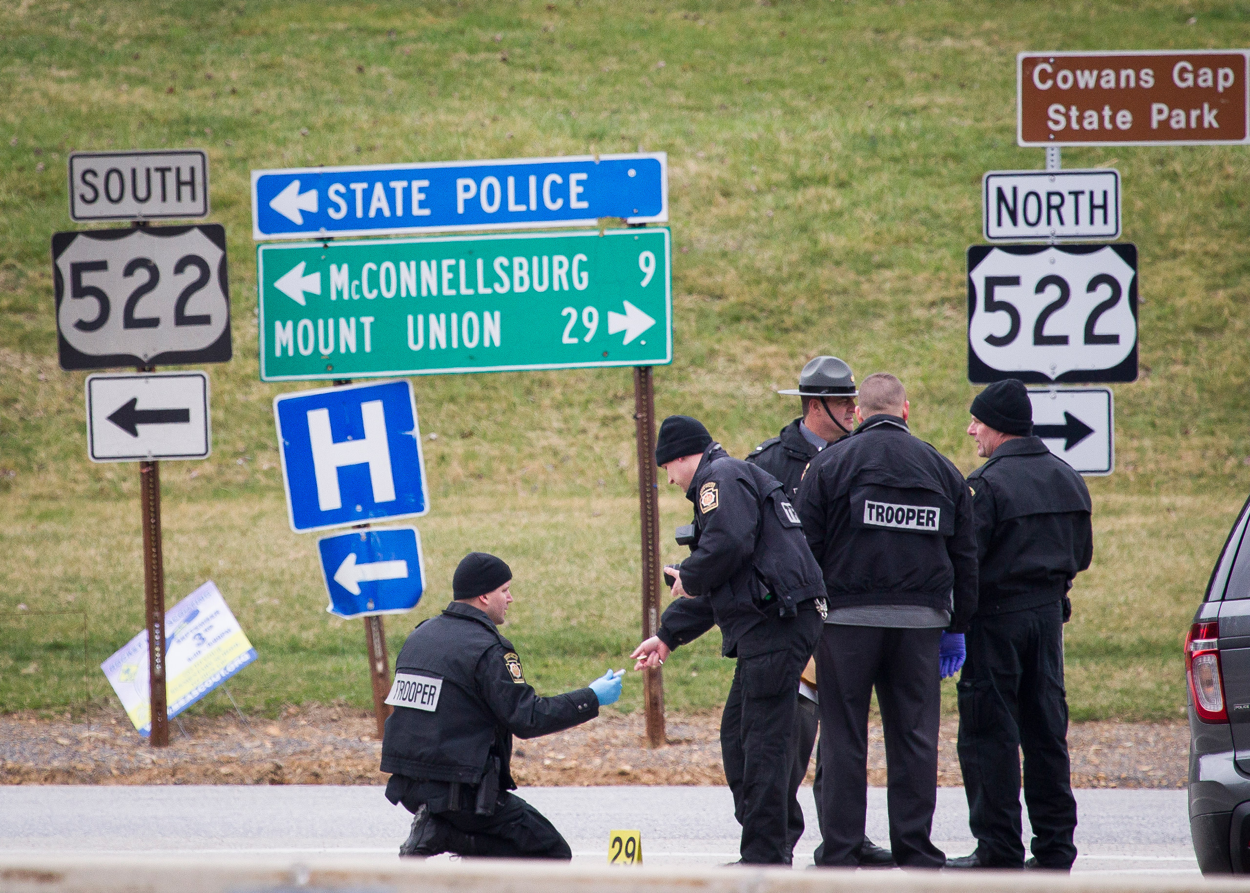 Police investigate at exit 180 off of the Pennsylvania Turnpike, Sunday, March 20, 2016, in Fort Littleton, Pa. A retired state trooper killed a turnpike toll collector and a security guard in a holdup attempt at a toll plaza and then was shot dead by tr