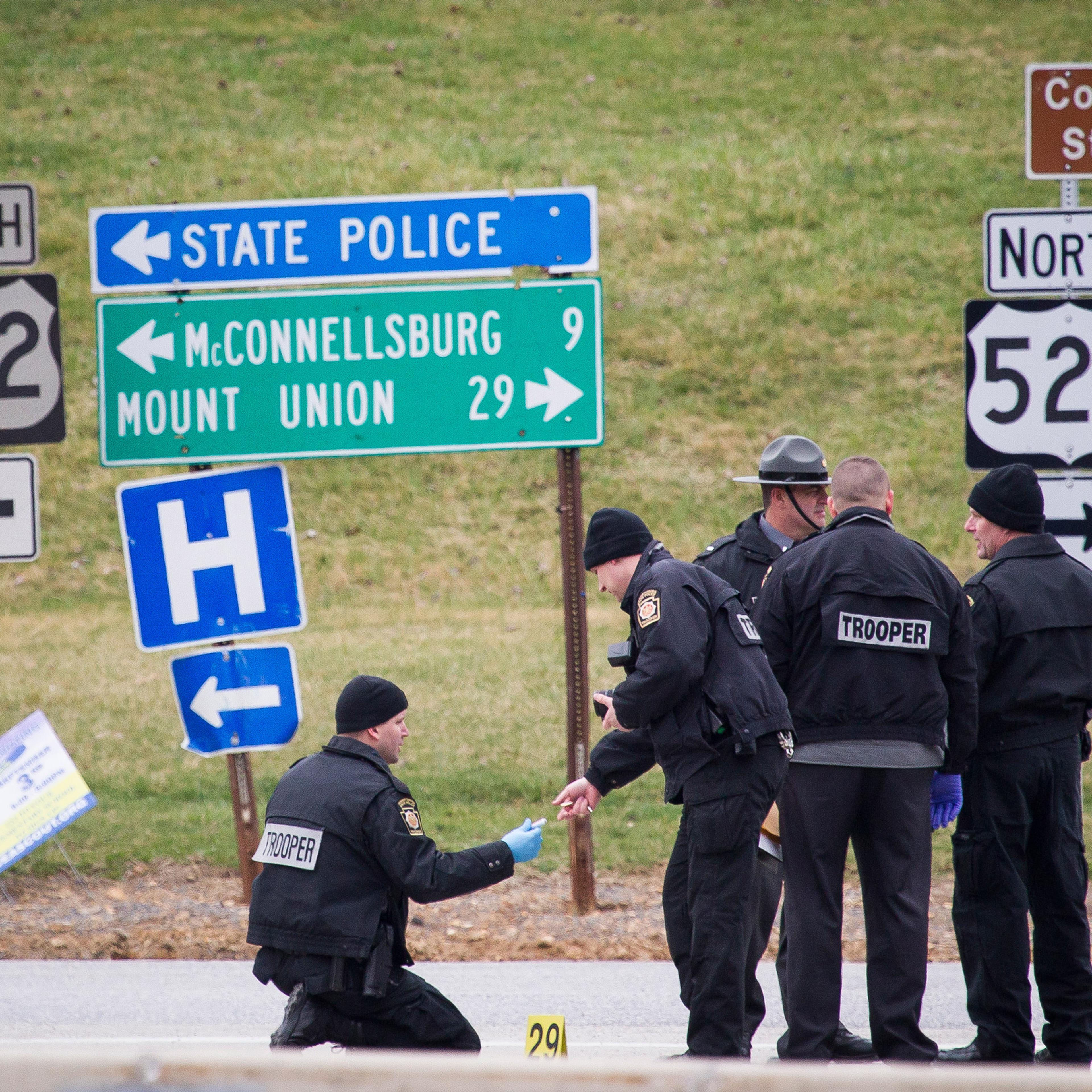 Police investigate at exit 180 off of the Pennsylvania Turnpike, Sunday, March 20, 2016, in Fort Littleton, Pa. A retired state trooper killed a turnpike toll collector and a security guard in a holdup attempt at a toll plaza and then was shot dead by tr