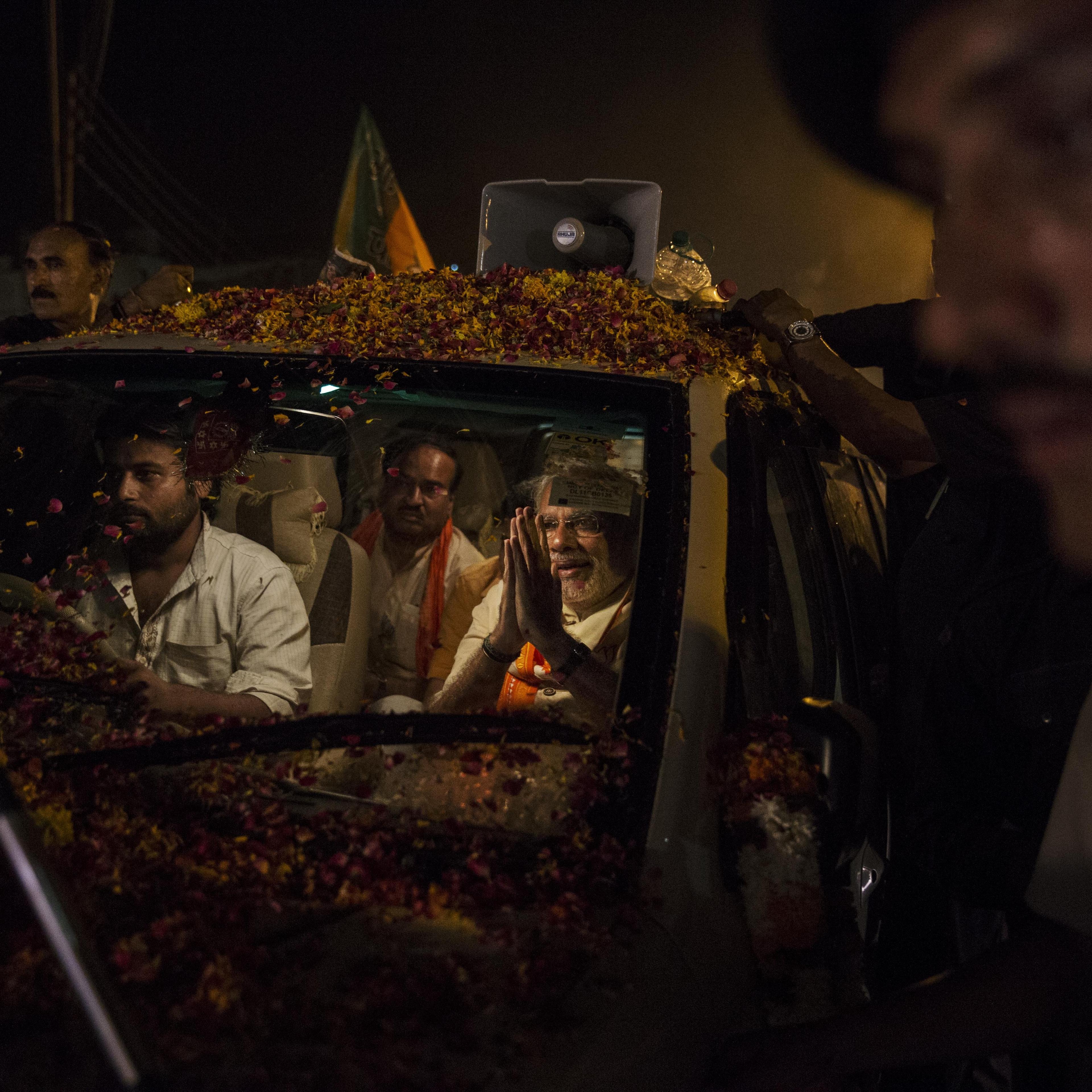 BJP leader Narendra Modi greets supporters as he is surrounded by bodyguards while driving through the streets on May 8, 2014 in Varanasi.