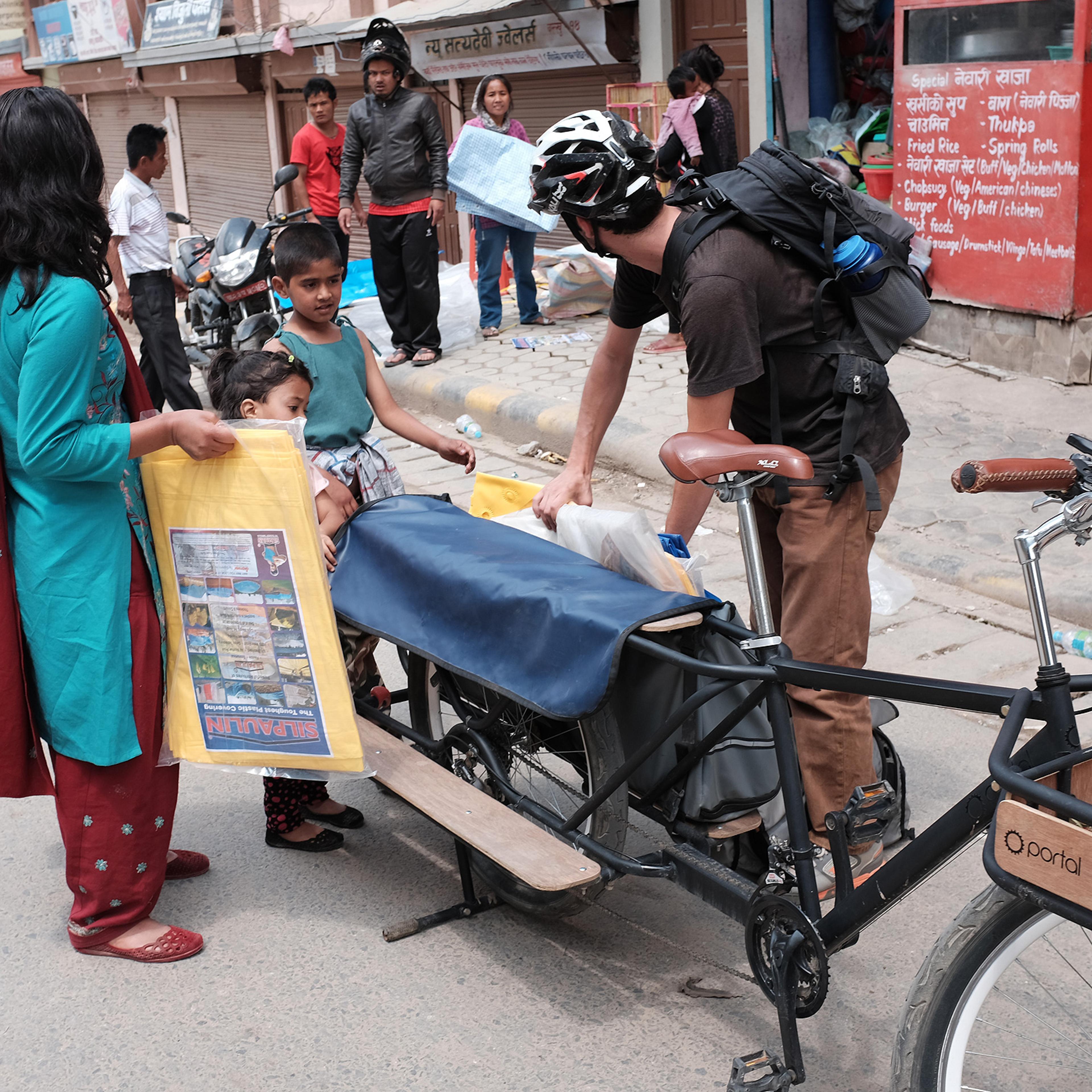 Mountain bike team member hands out tarpaulin in villages in need of relief after the Nepal earthquake of April 25, 2015