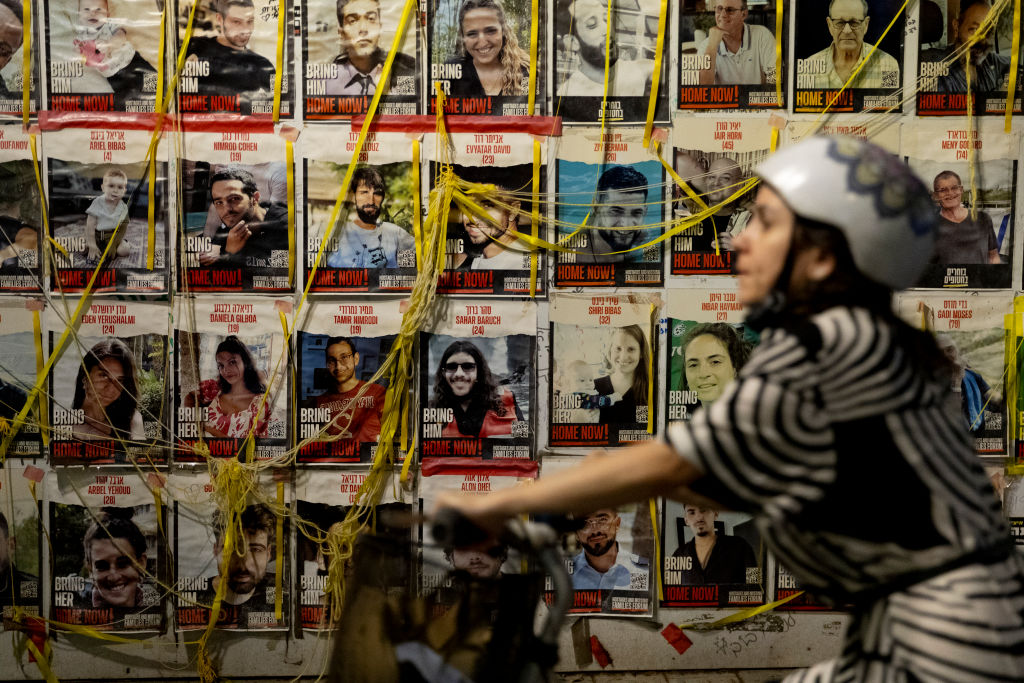 A woman passes by photos of hostages held in Gaza, pasted on a wall in Tel Aviv, Israel, on July 24, 2024.