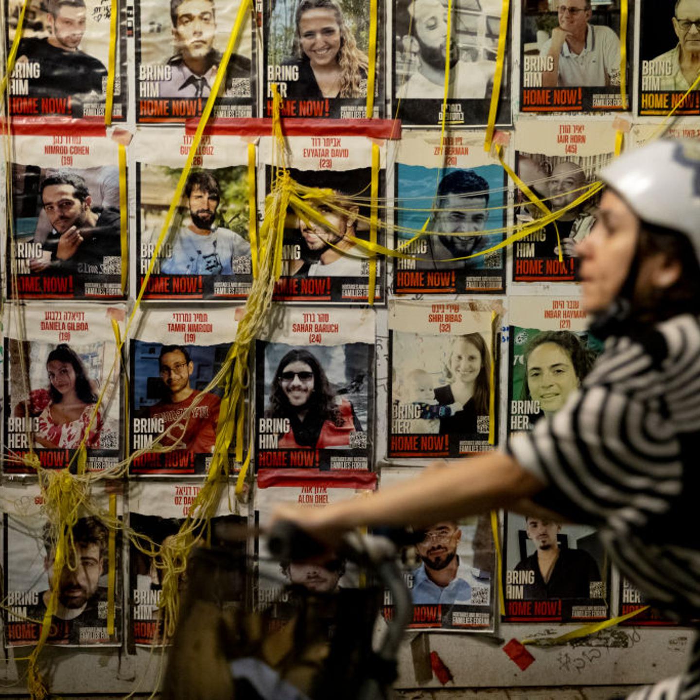 A woman passes by photos of hostages held in Gaza, pasted on a wall in Tel Aviv, Israel, on July 24, 2024.