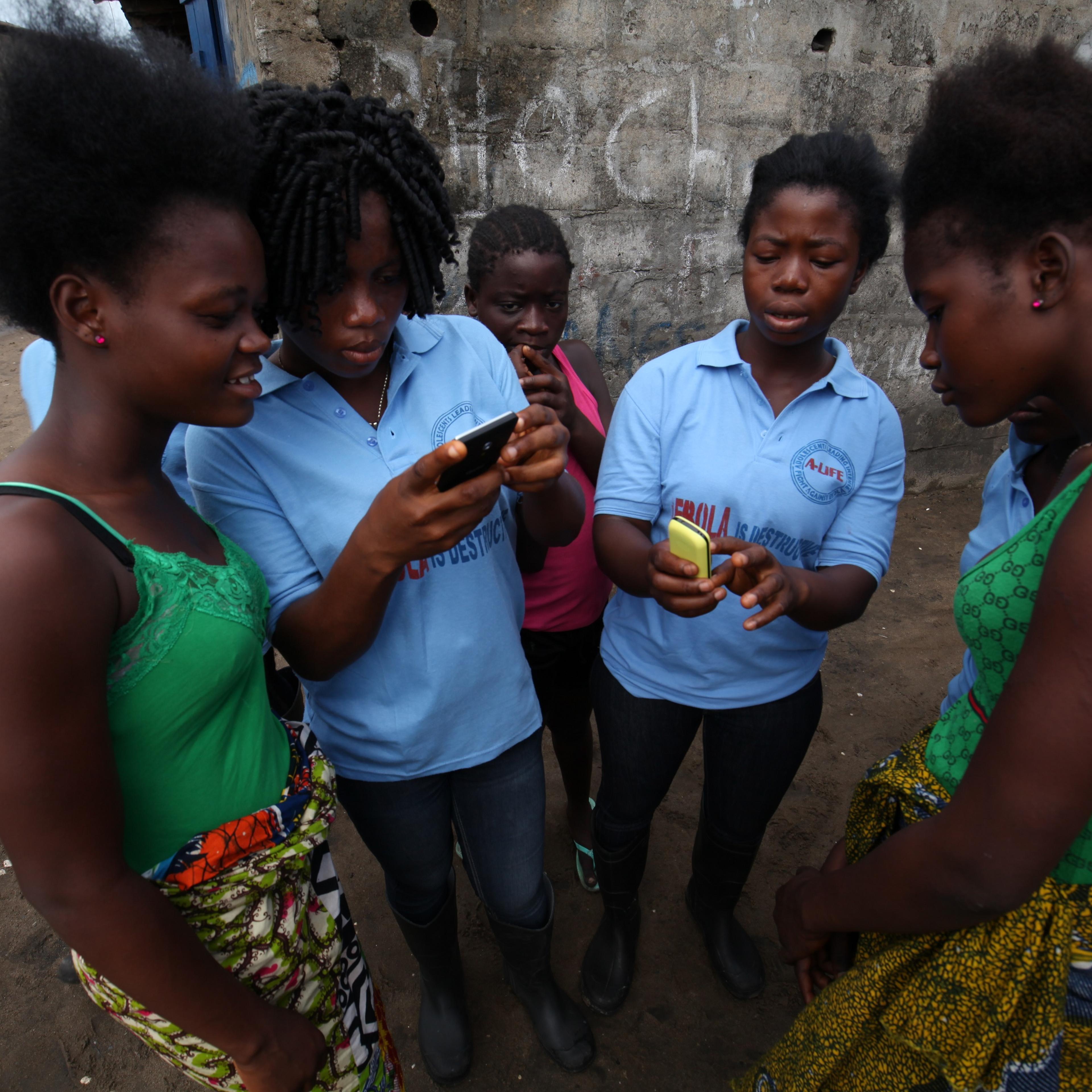 Volunteers from the A-Life adolescents group help youth in West Point, Monrovia, Liberia register on U-Report, a sms-based platform that enables over 71,000 youth to receive information and share issues that are relevant to them.
