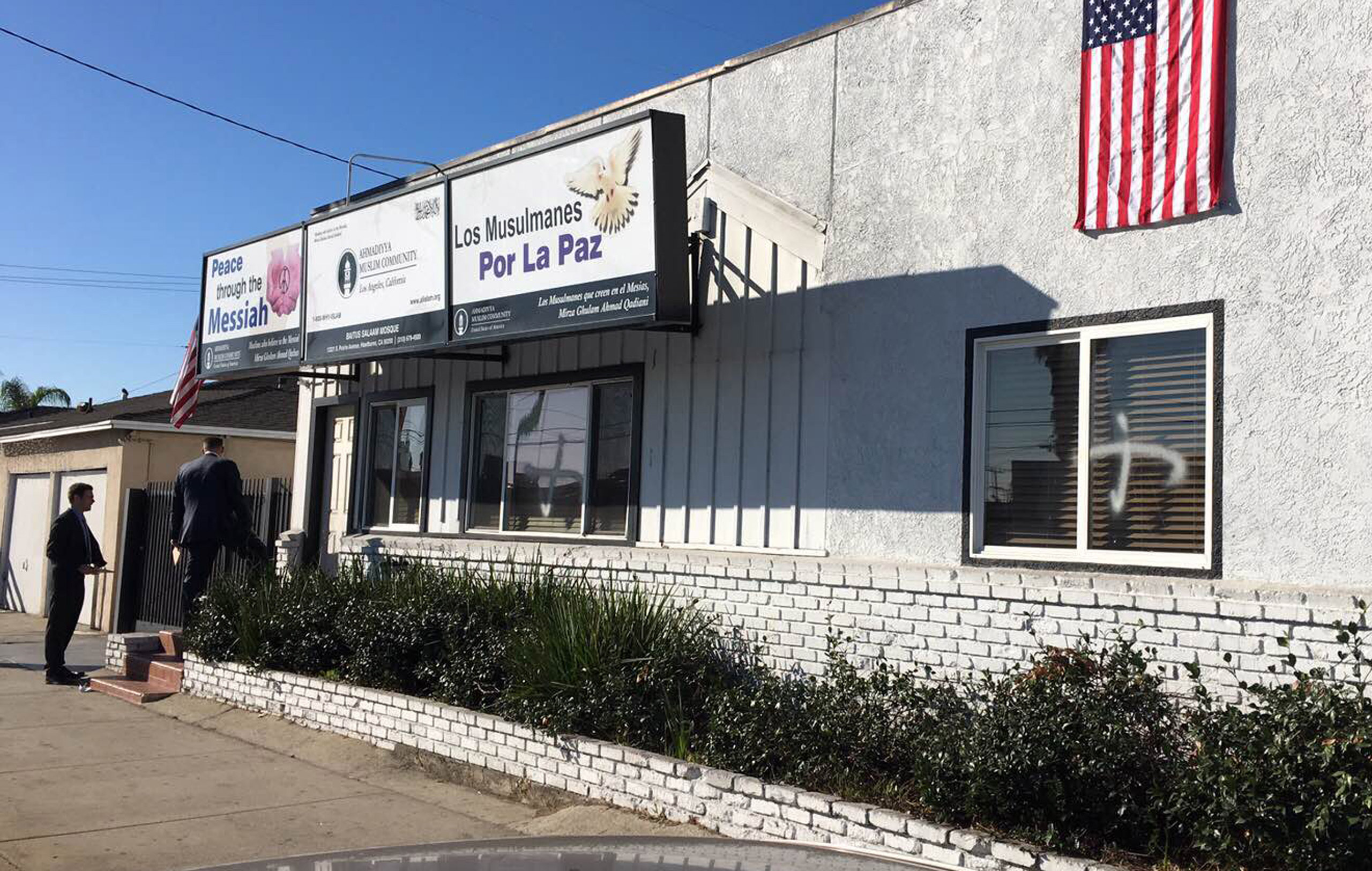 This photo provided by the Ahmadiyya Muslim Community muslimsforpeace.org shows crosses in spray paint vandalizing windows at the Ahmadiyya Muslim Community Baitus-Salaam Mosque in Hawthorne, Calif., Sunday, Dec. 13, 2015. The FBI is investigating after 