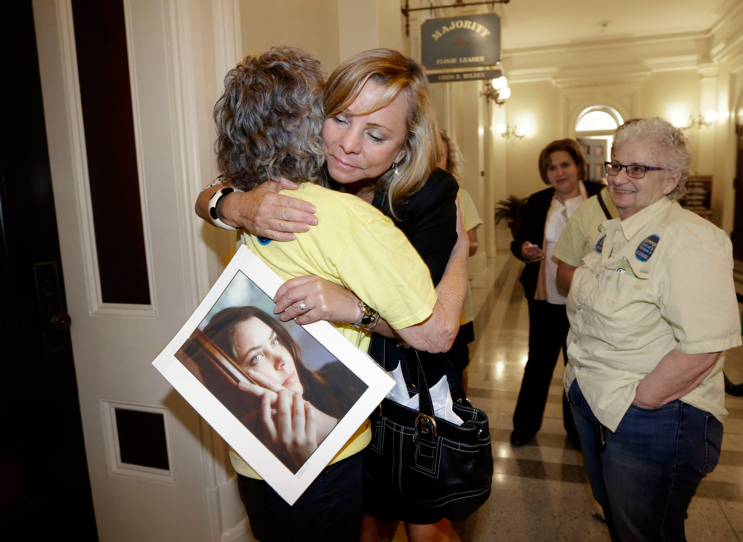 Debbie Ziegler holds a photo of her daughter, Brittany Maynard, as she receives congratulations from Ellen Pontac, after a right-to die measure was approved by the state Assembly, Wednesday, Sept. 9, 2015, in Sacramento, Calif. The bill, approved on a 42