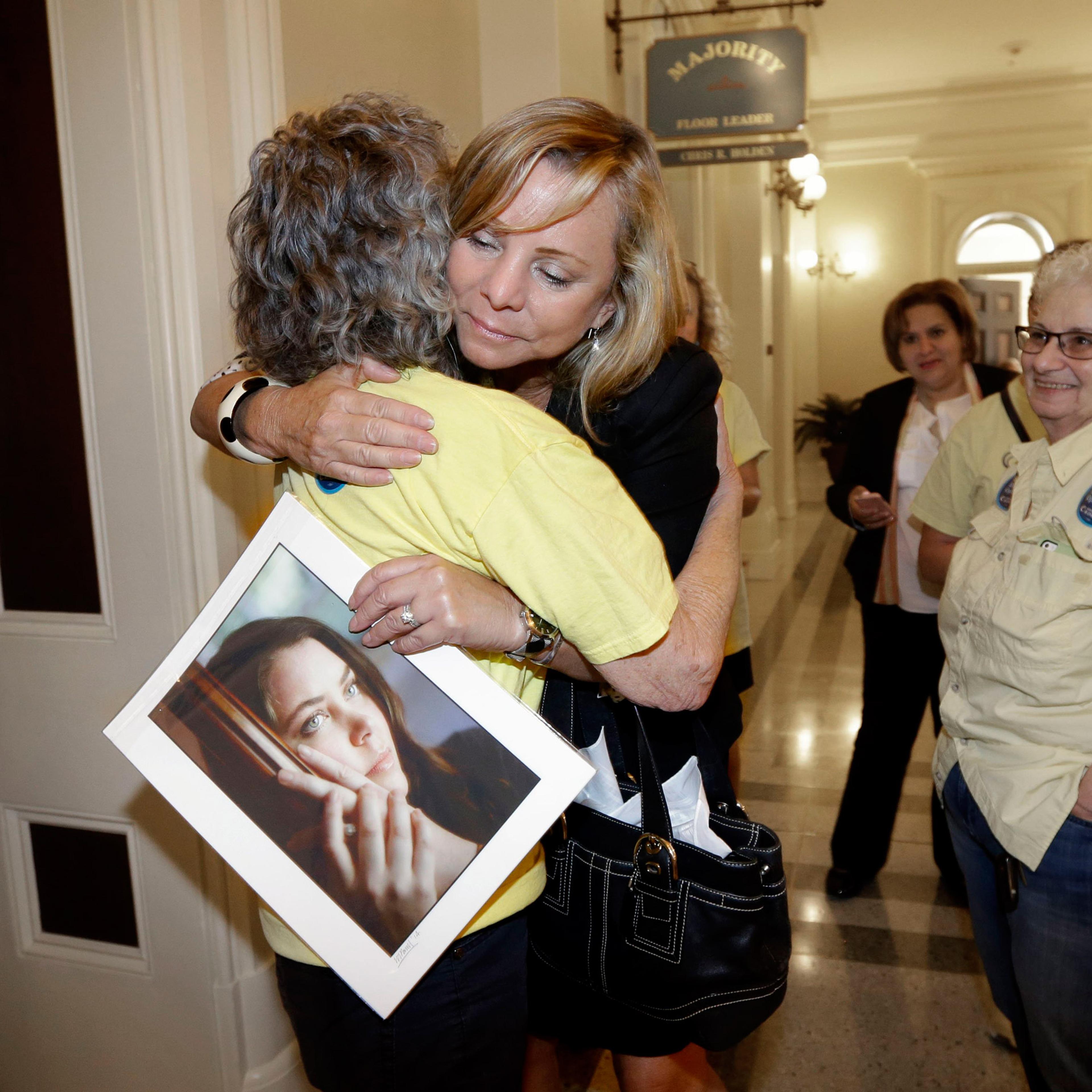 Debbie Ziegler holds a photo of her daughter, Brittany Maynard, as she receives congratulations from Ellen Pontac, after a right-to die measure was approved by the state Assembly, Wednesday, Sept. 9, 2015, in Sacramento, Calif. The bill, approved on a 42