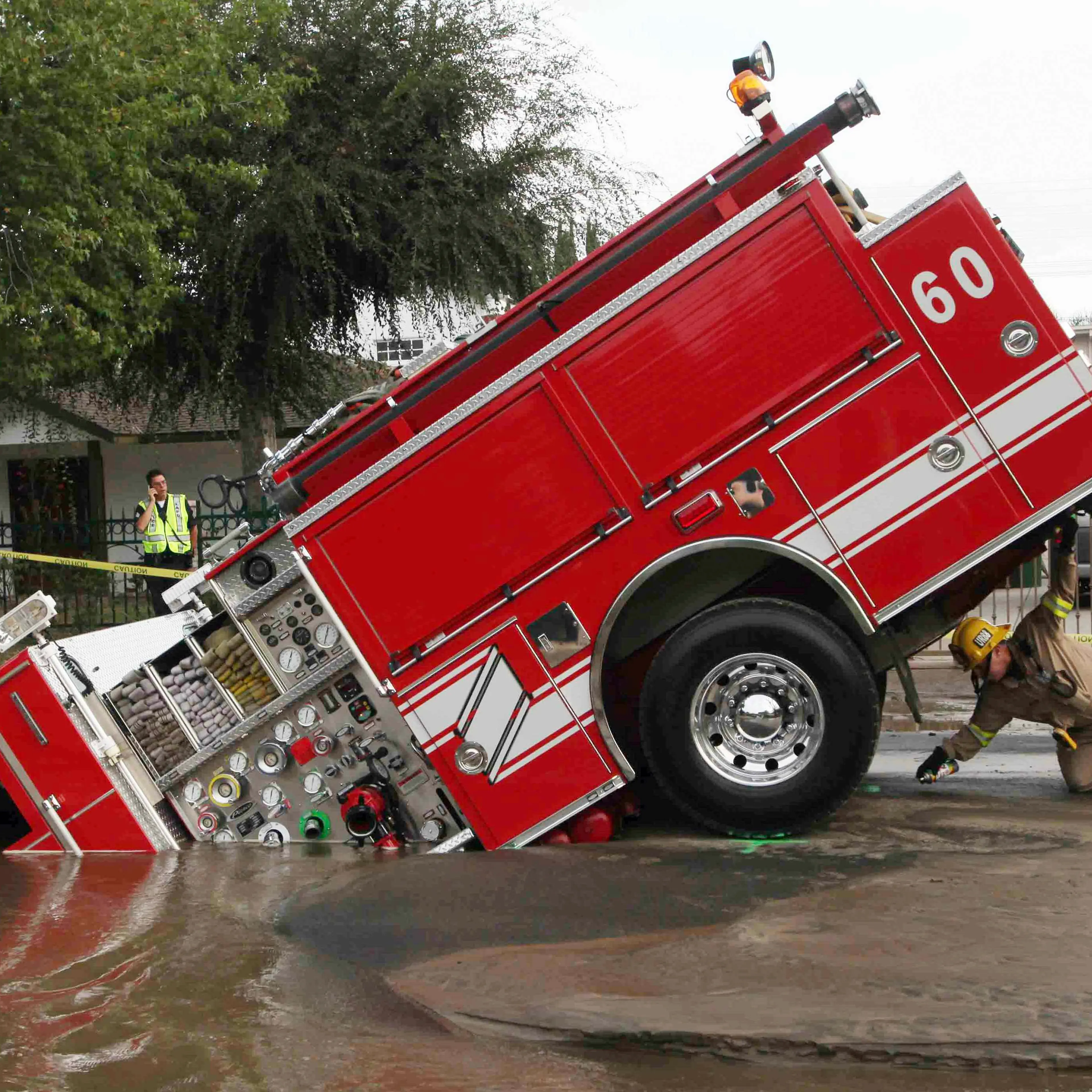 A Los Angeles fireman looks under a fire truck stuck in a sinkhole in the Valley Village neighborhood of Los Angeles, Sept. 8, 2009. Four firefighters escaped injury early Tuesday after their fire engine sunk into a large hole caused by a burst water mai