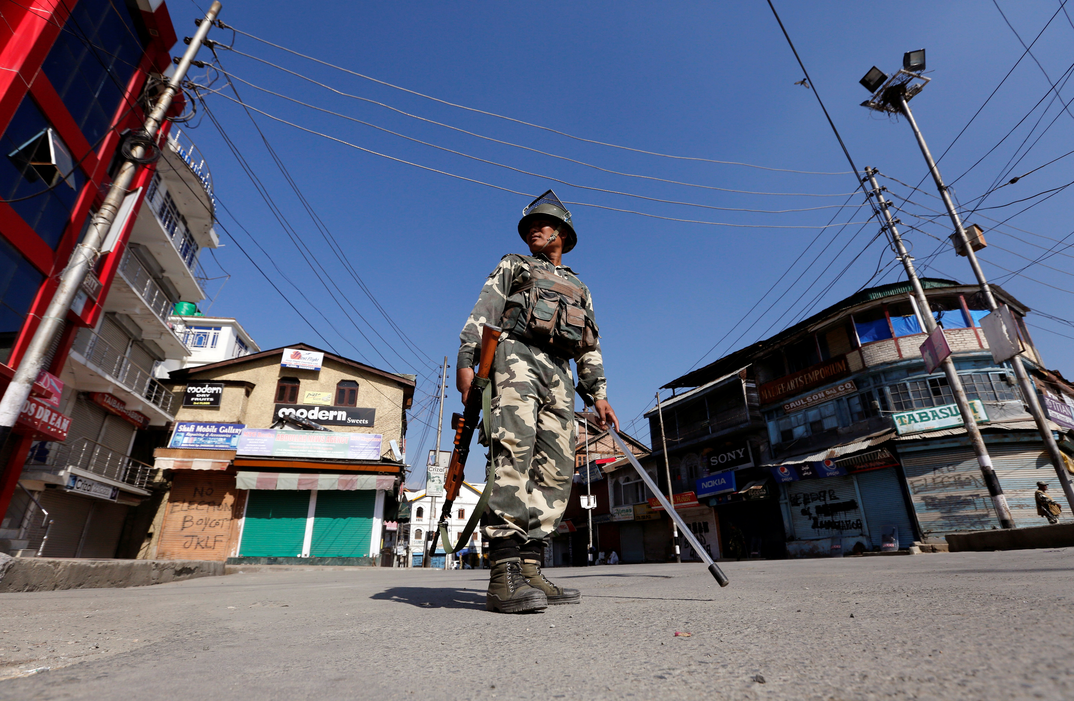 An Indian policeman stands guard in a deserted street during a curfew in Srinagar