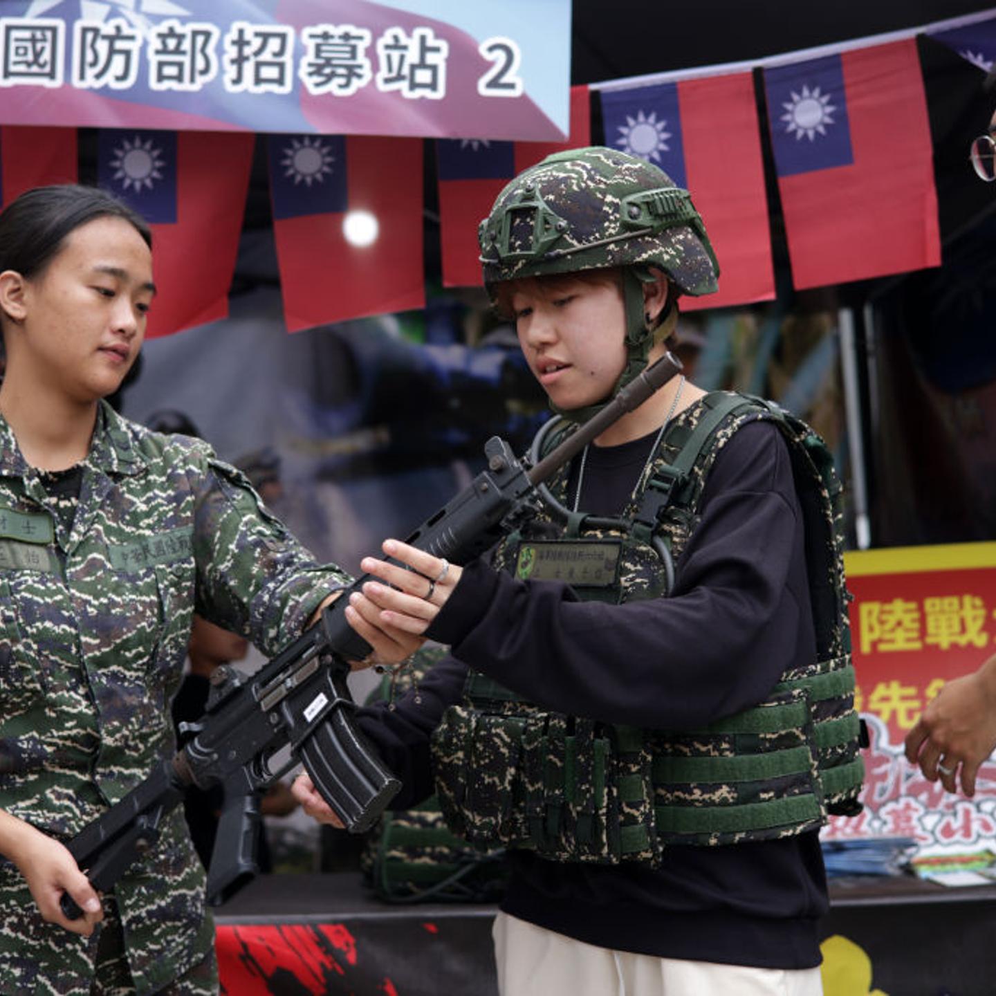 A visitor tries military outfit and holds a rifle at an Army recruiting booth at a pre-National Day street fair, on October 09, 2023 in New Taipei City, Taiwan.