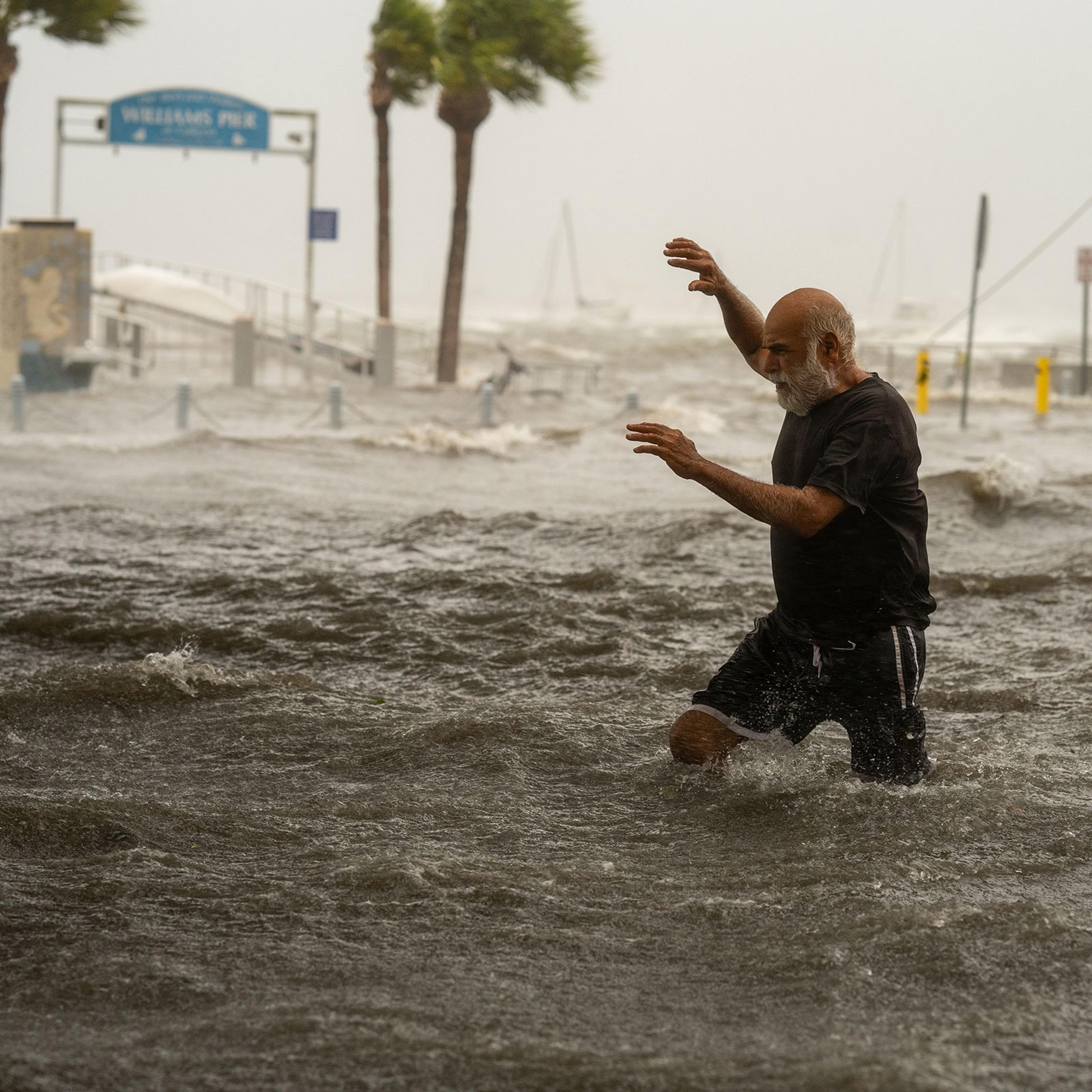 A man crosses a storm surge flooded area on the coast of Gulfport, Fla. on Sept. 26, 2024.