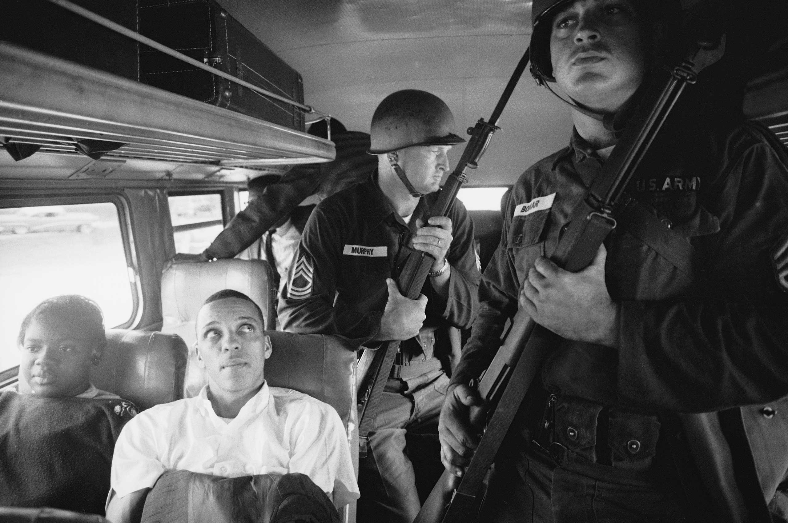 Freedom Riders Julia Aaron and David Dennis sit aboard an interstate bus as they and 25 other civil rights activists are escorted by Mississippi National Guardsmen on a violence-marred trip between Montgomery, Alabama, and Jackson, Mississippi. Originall