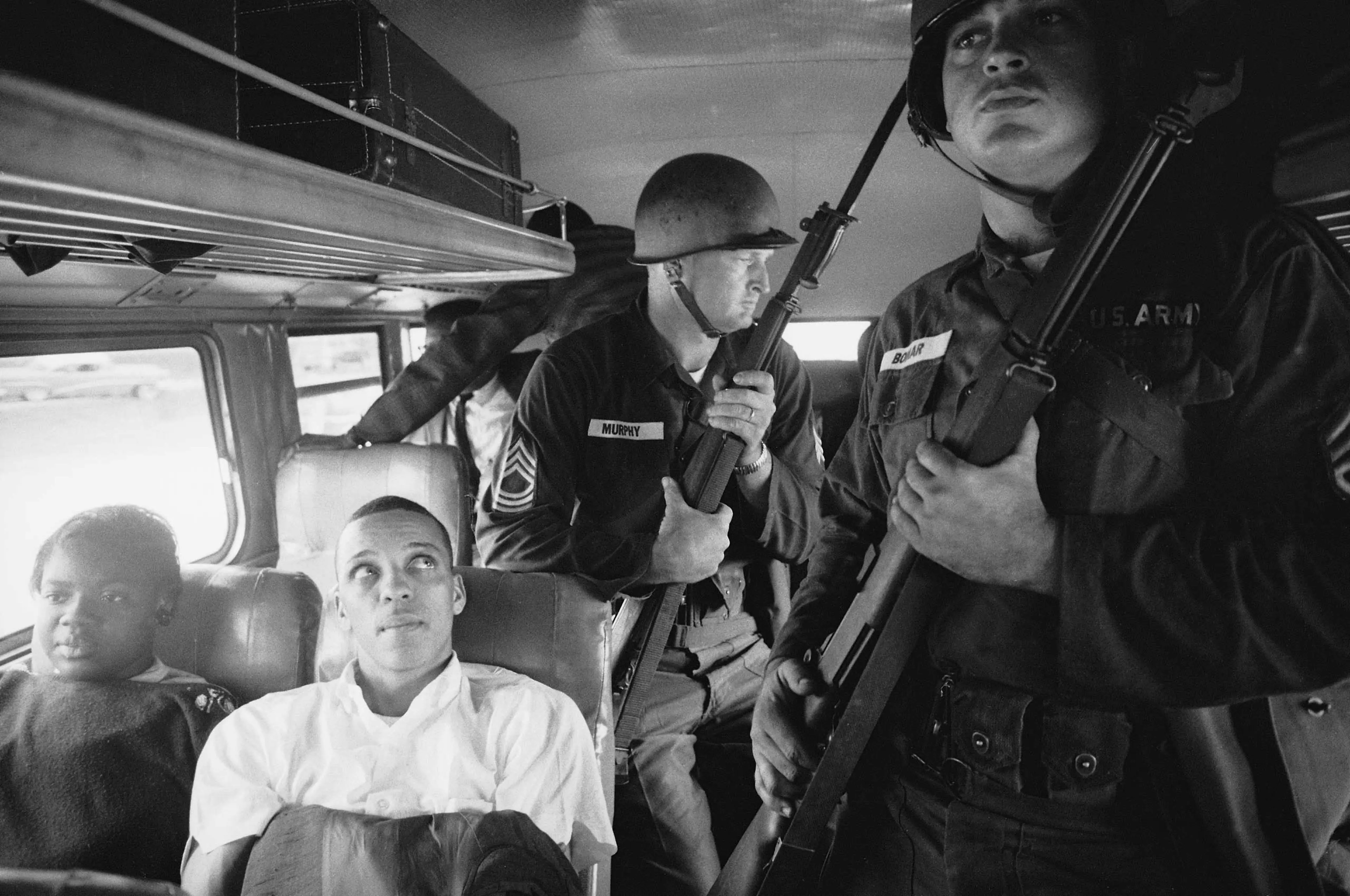 Freedom Riders Julia Aaron and David Dennis sit aboard an interstate bus as they and 25 other civil rights activists are escorted by Mississippi National Guardsmen on a violence-marred trip between Montgomery, Alabama, and Jackson, Mississippi. Originall